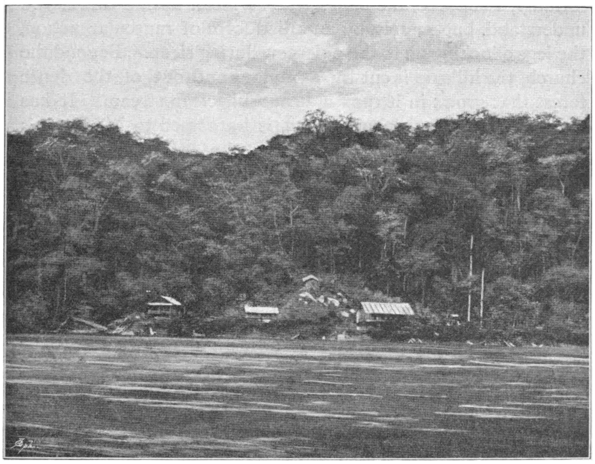 Buildings of the Talagouga mission station beneath a wooded hillside on the bank of a broad river