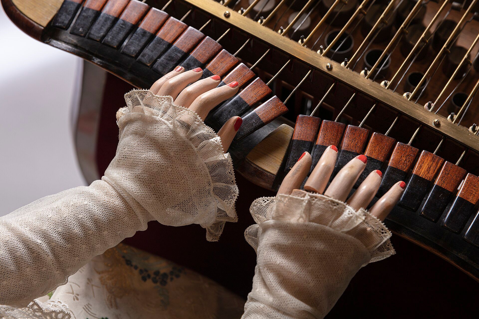 Close view of the Musician’s hands above the organ keys, with rods and fittings visible beneath.