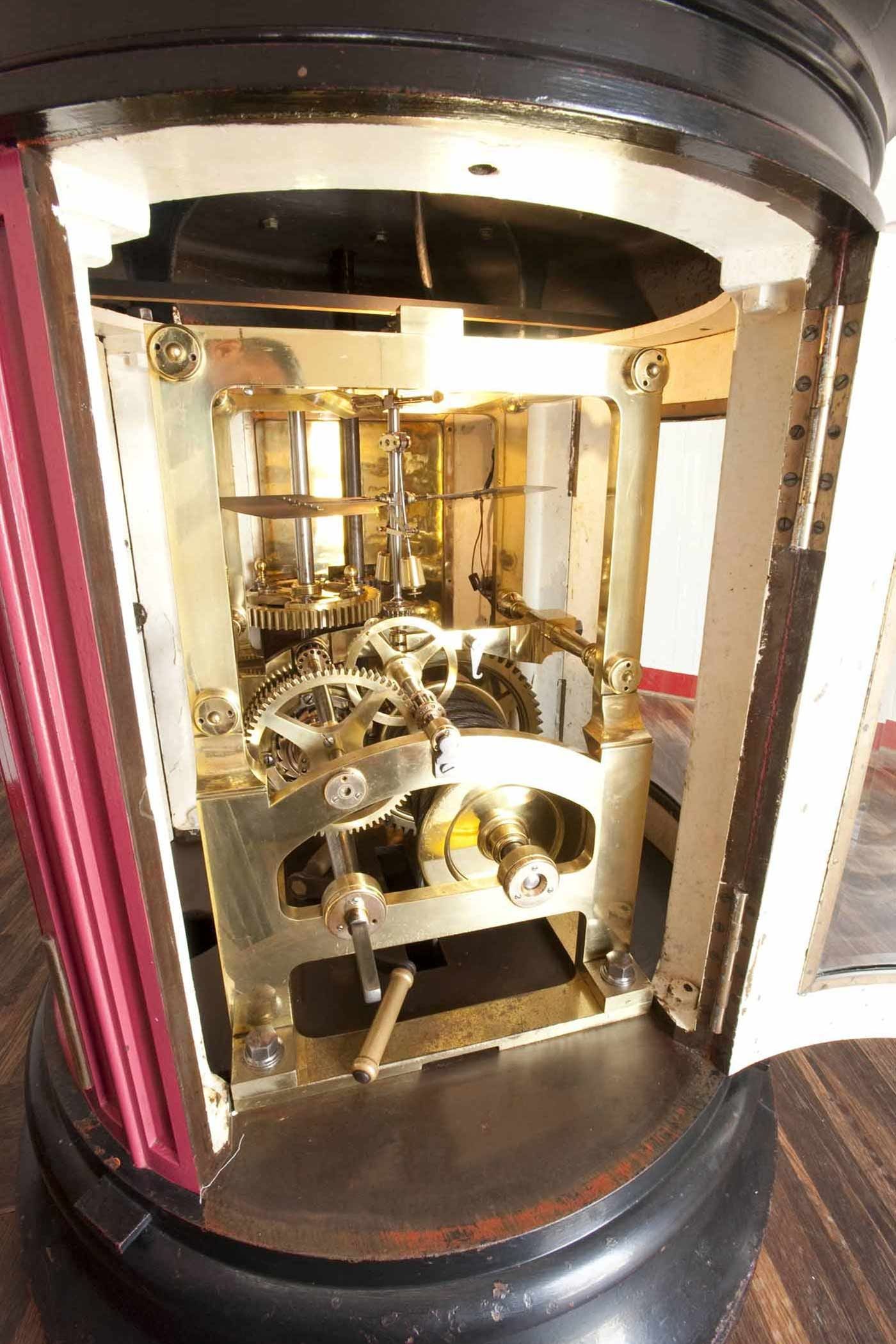 The open brass clockwork case beneath the Point Reyes lens, revealing gears and shafts