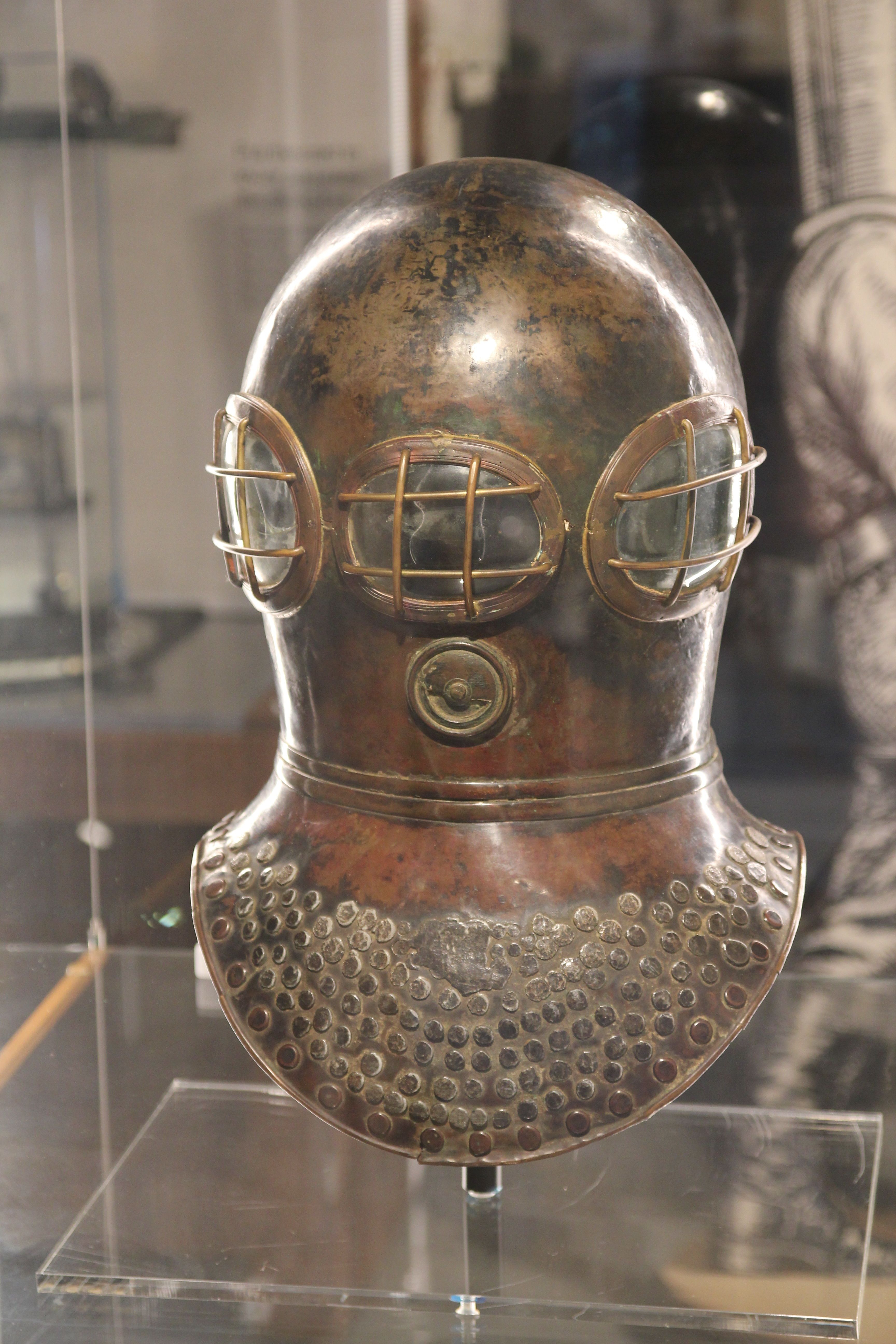 A surviving copper Deane smoke and diving helmet with three guarded windows and a broad perforated shoulder plate