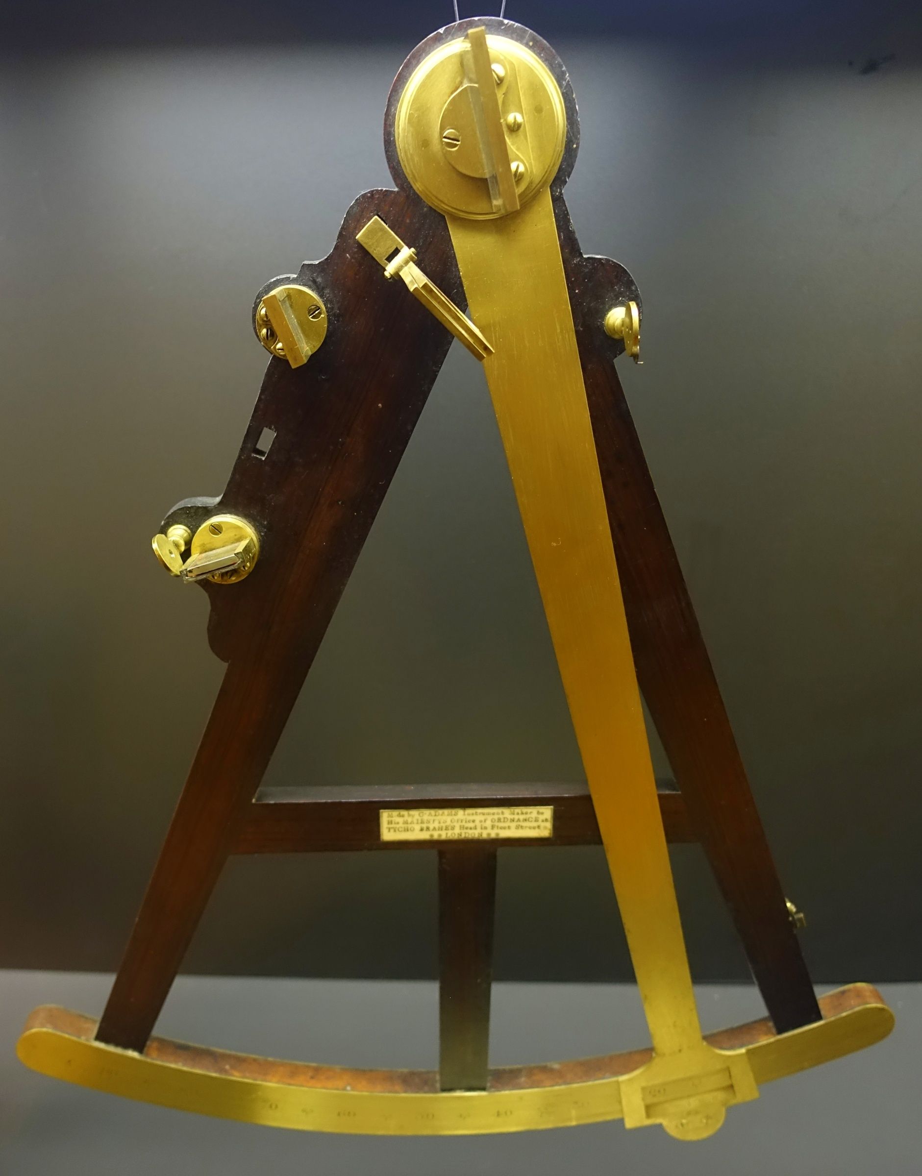 A wooden-framed octant with a brass index arm crossing its triangular opening and curved lower scale