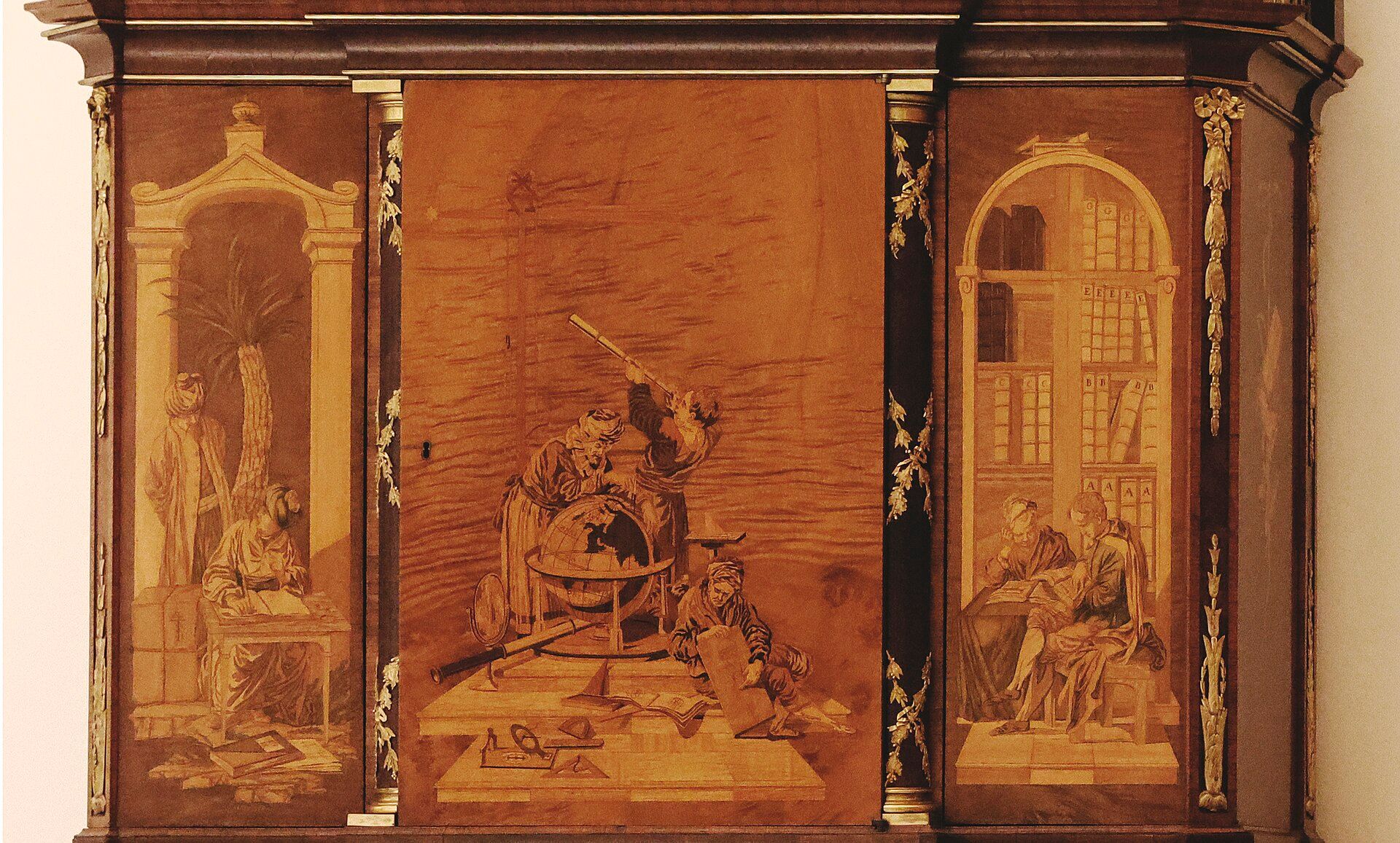 A marquetry scene with figures fitted into the doors of an ornate wooden cabinet.