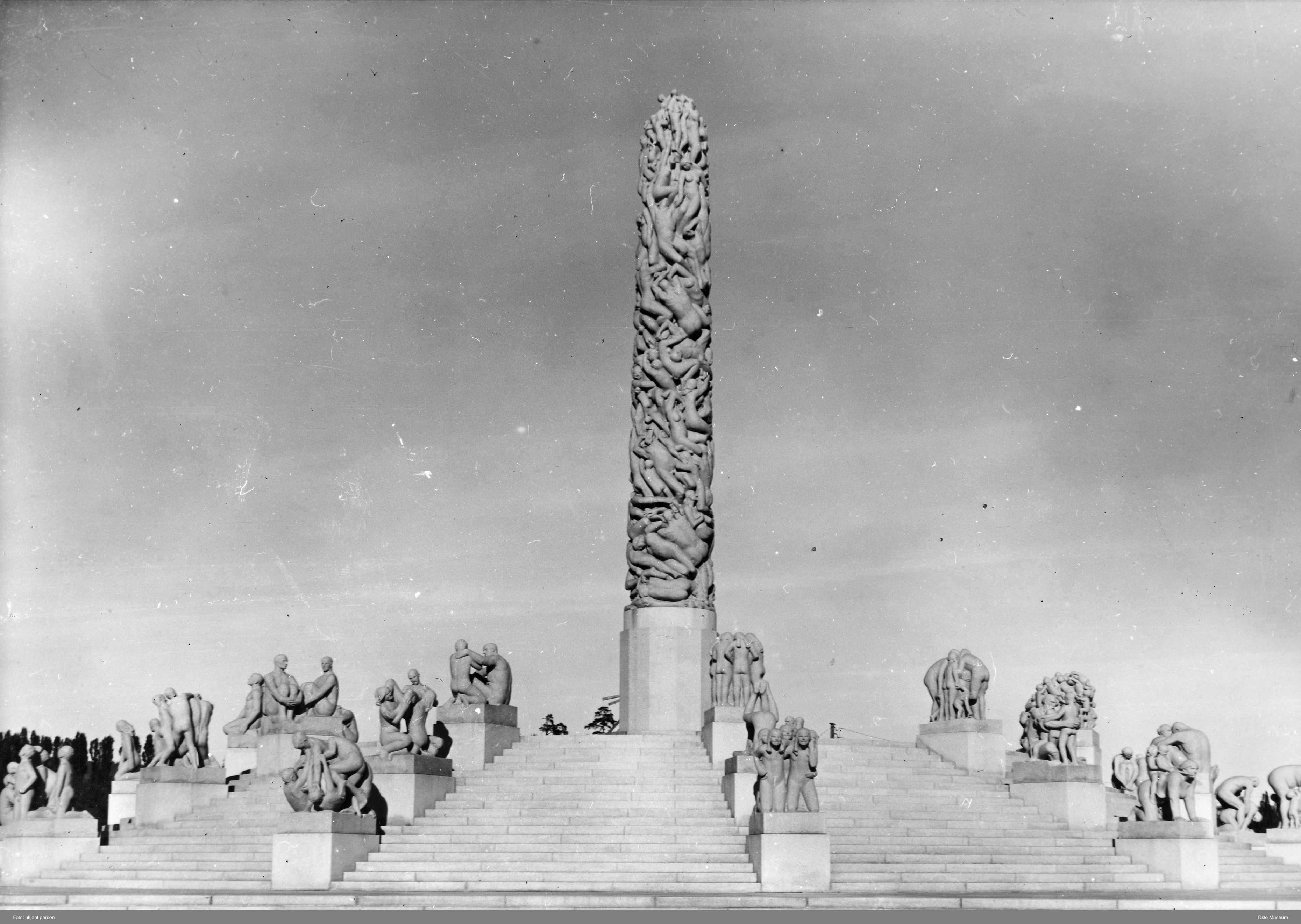 The completed Monolith standing in the open air above broad steps and surrounding granite figure groups in Vigeland Park.
