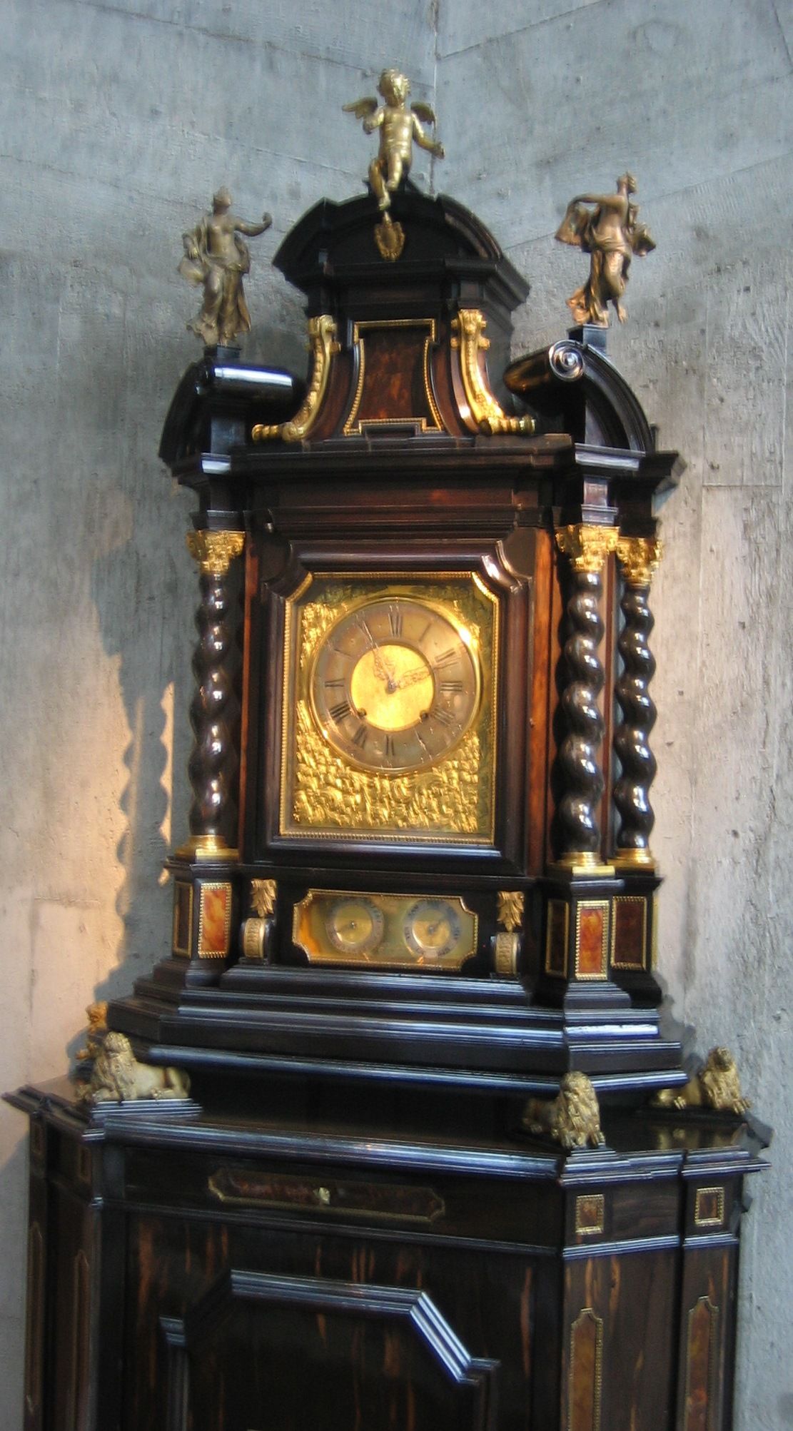 A Jaquet-Droz clock with a large circular dial above a decorated pedestal.