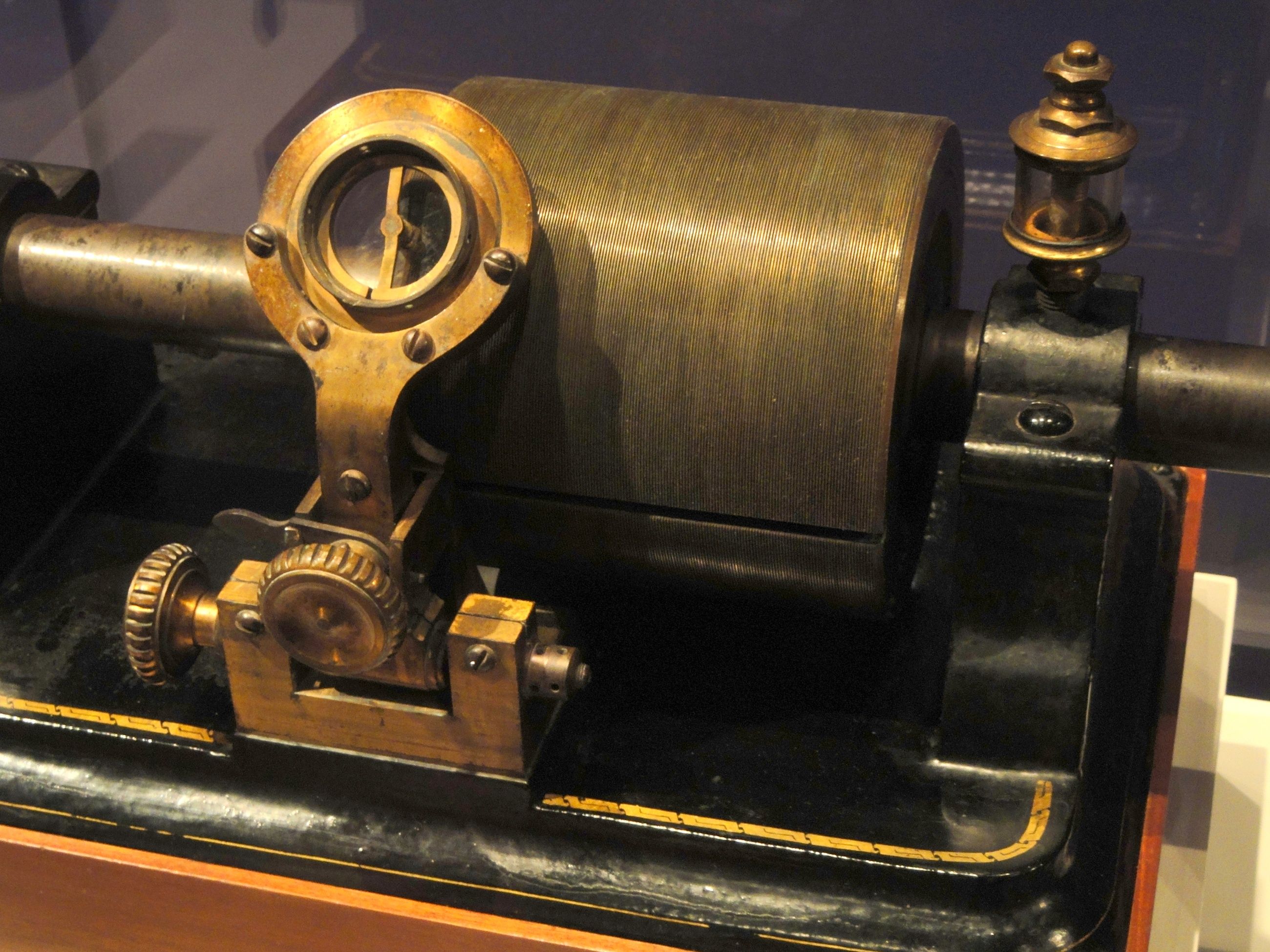 Grooved cylinder, round diaphragm mounting and adjustment wheels on a brass and black phonograph