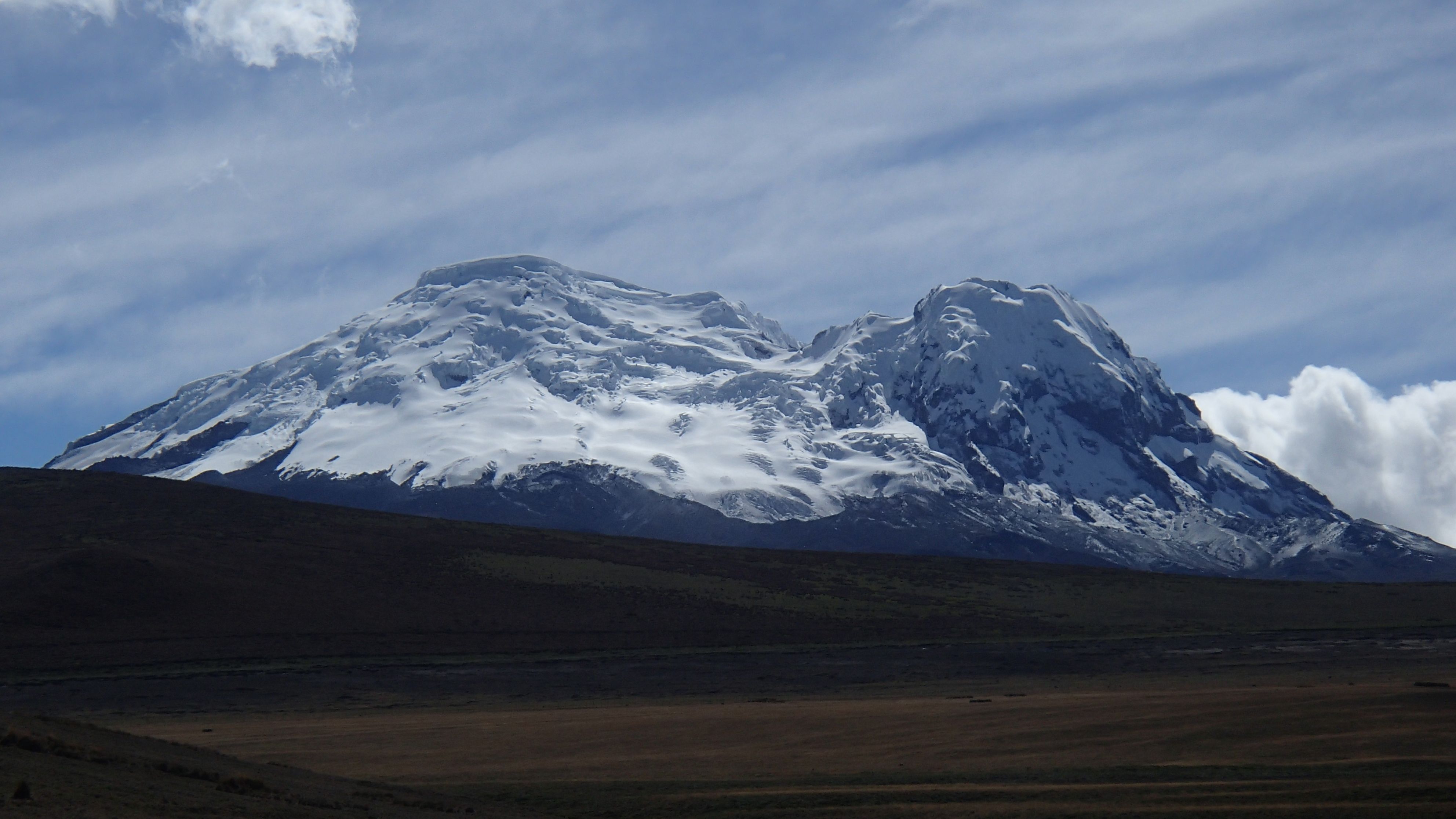 The snowy Antisana volcano rising above open highland vegetation, photographed from the west