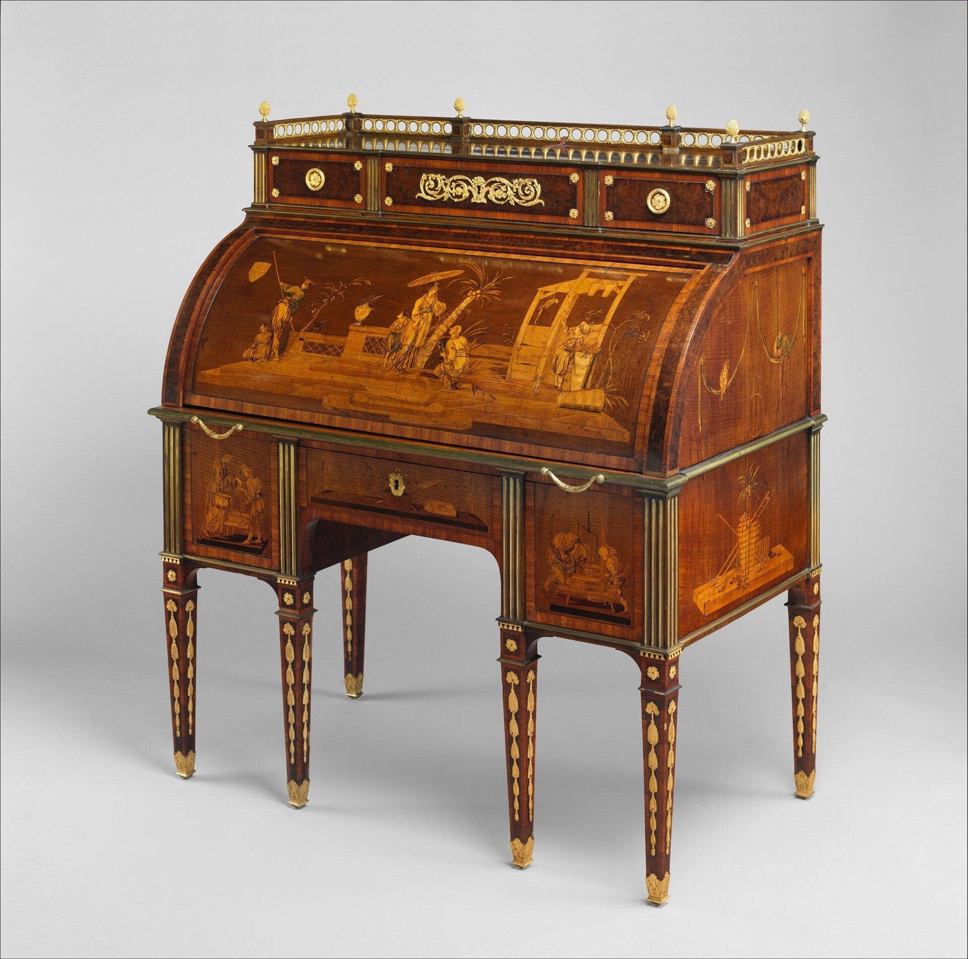 A six-legged wooden desk with a closed curved top, pictorial marquetry and gilt-bronze mounts.