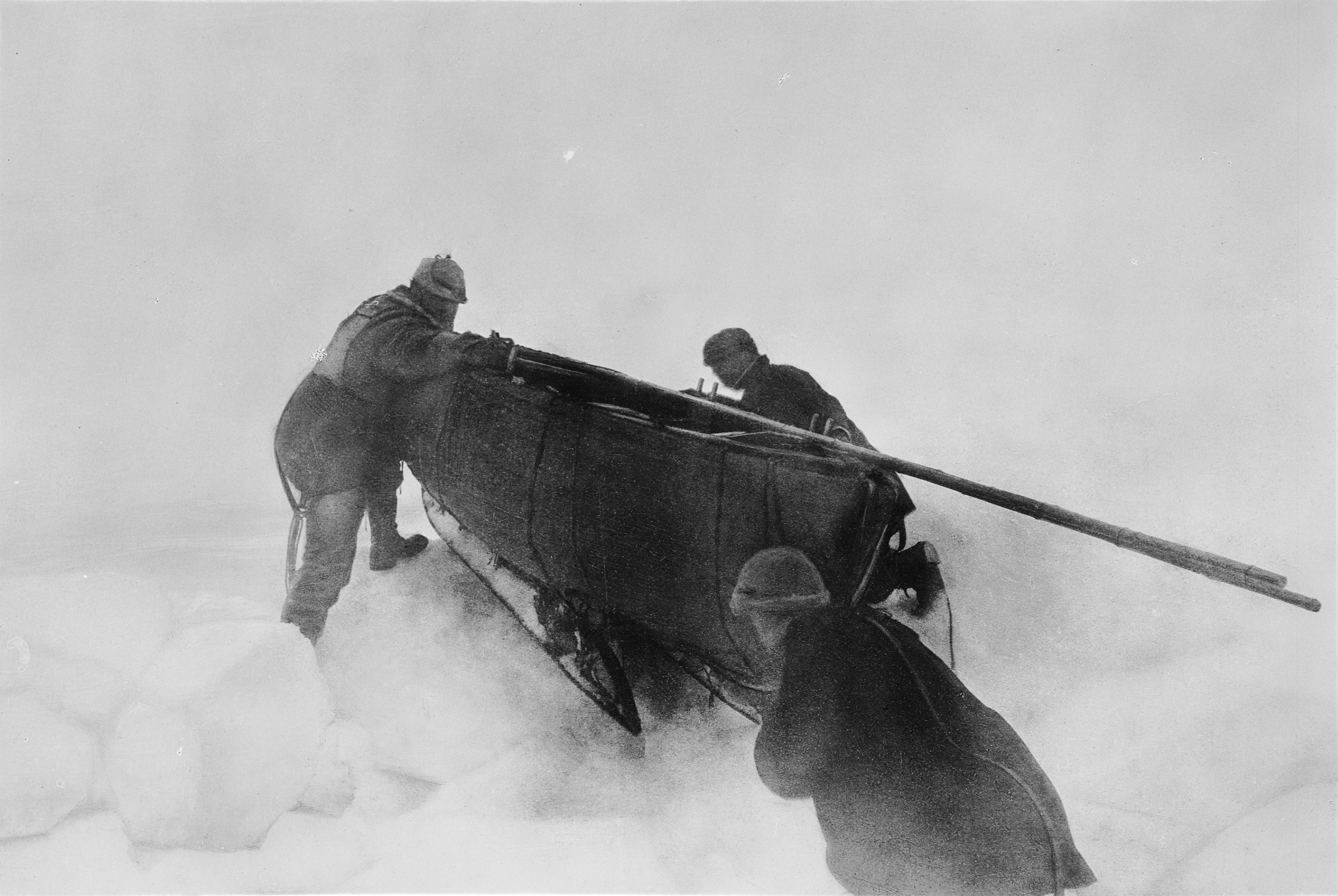 Three men working around the loaded boat and sledge at a ridge in the ice