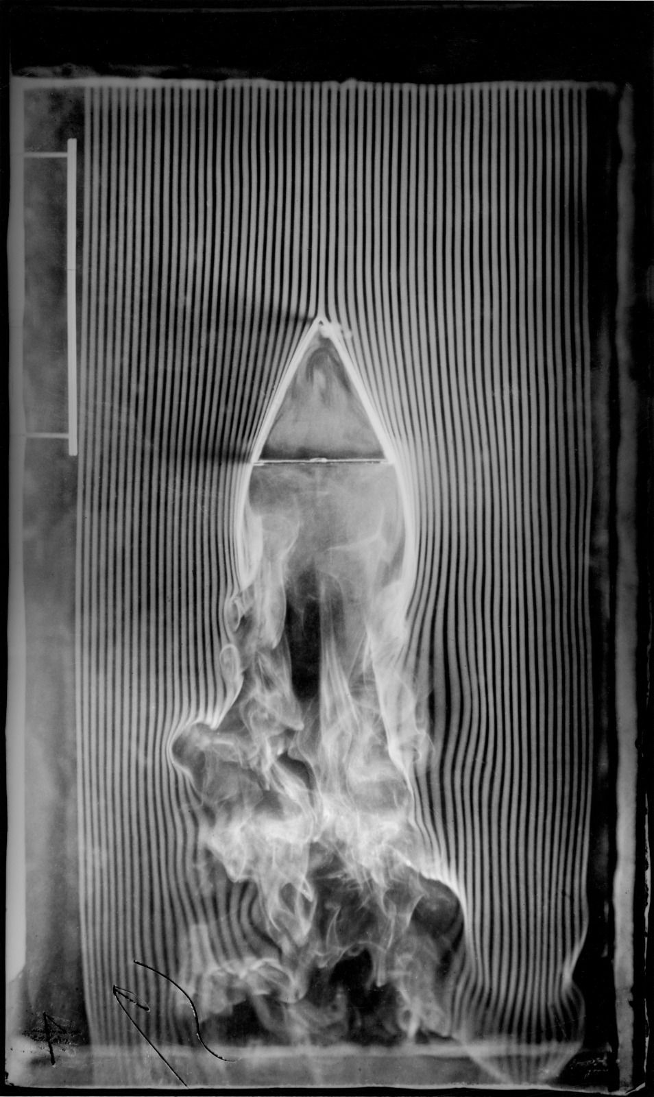 A triangular prism points upward into the incoming smoke, which divides along its sides and curls beneath its broad lower face.