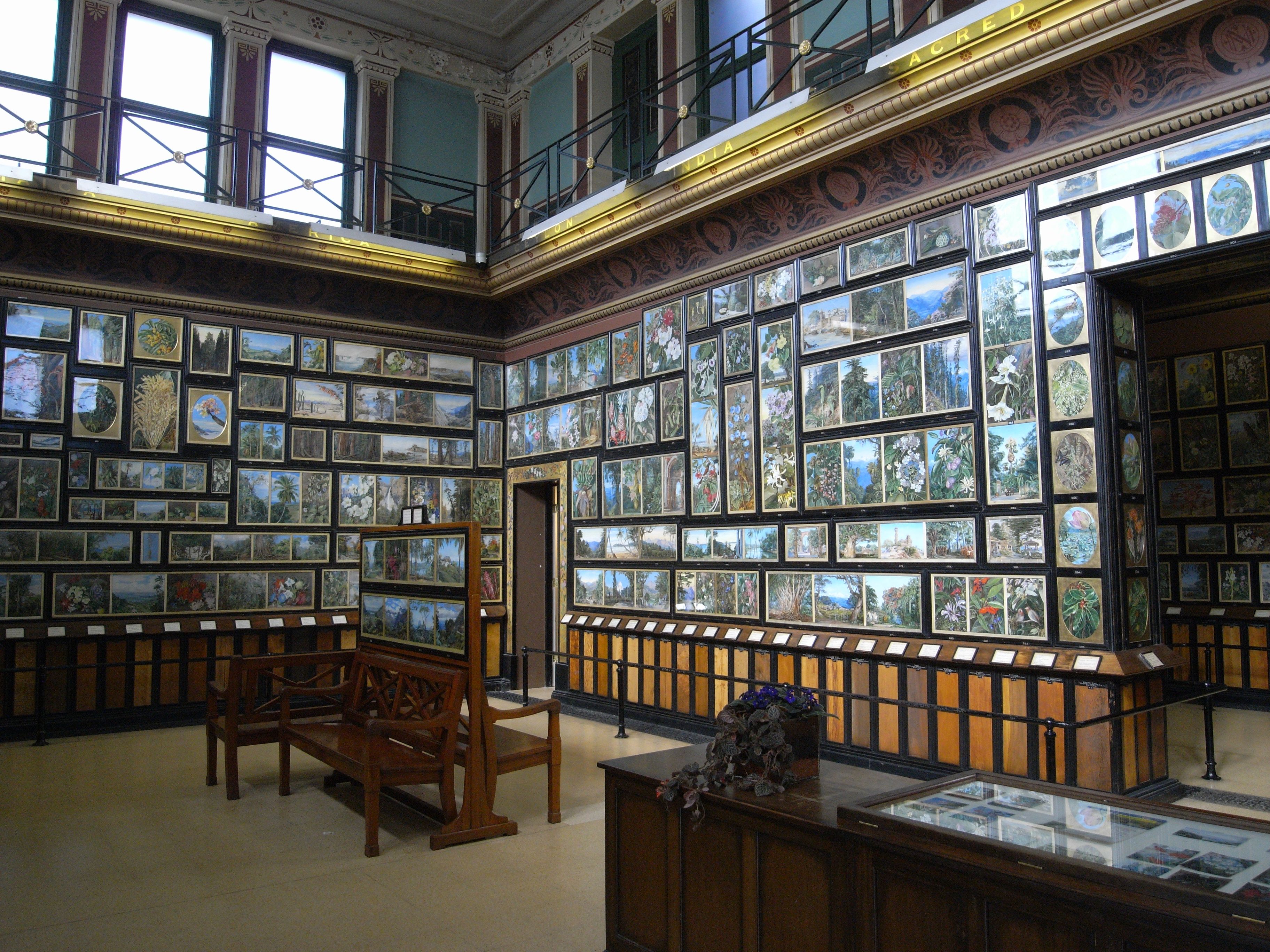 Closely hung paintings covering the walls of the gallery above panels of different woods.