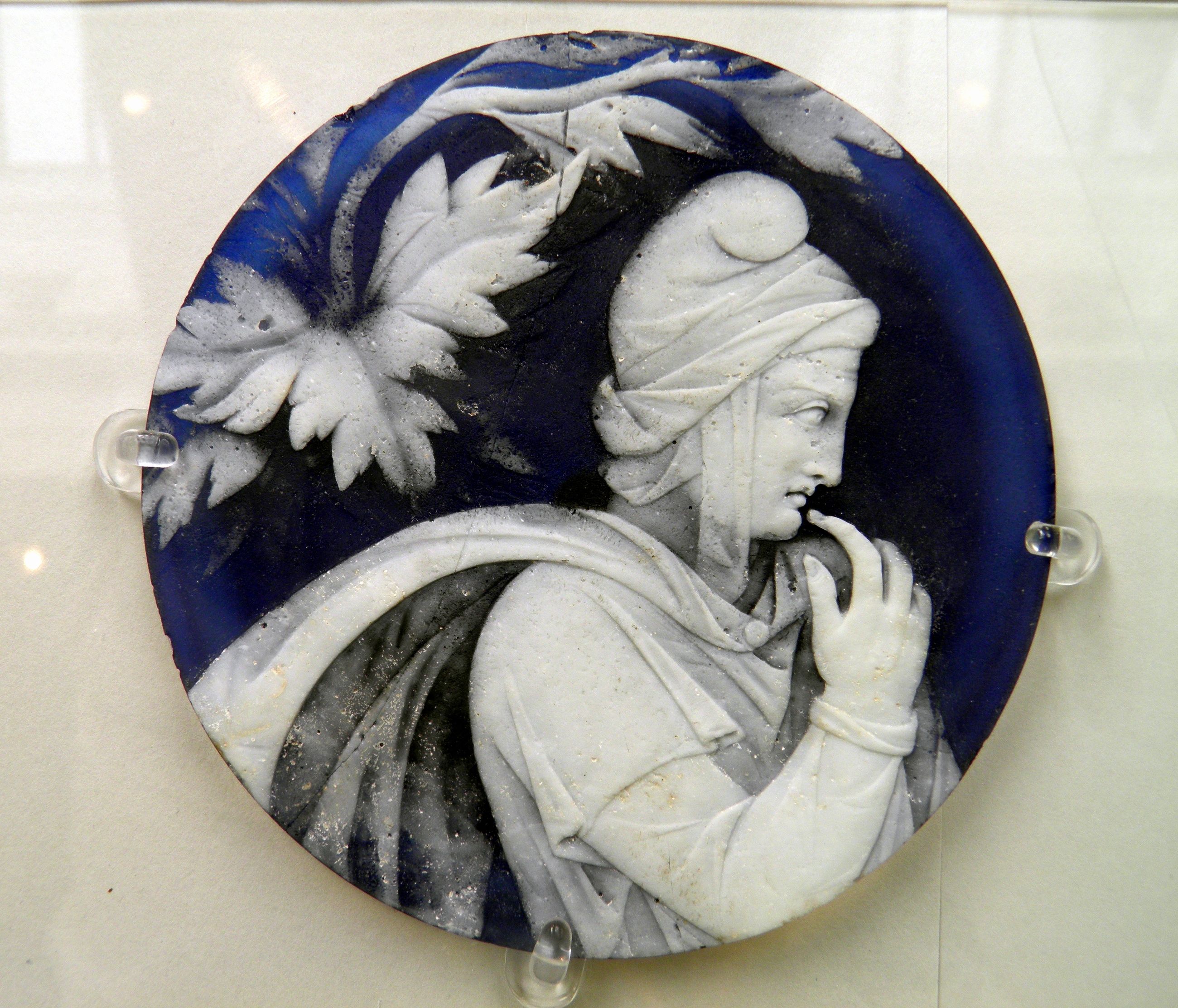 A separate blue and white ancient cameo disc with a head in profile and a raised hand