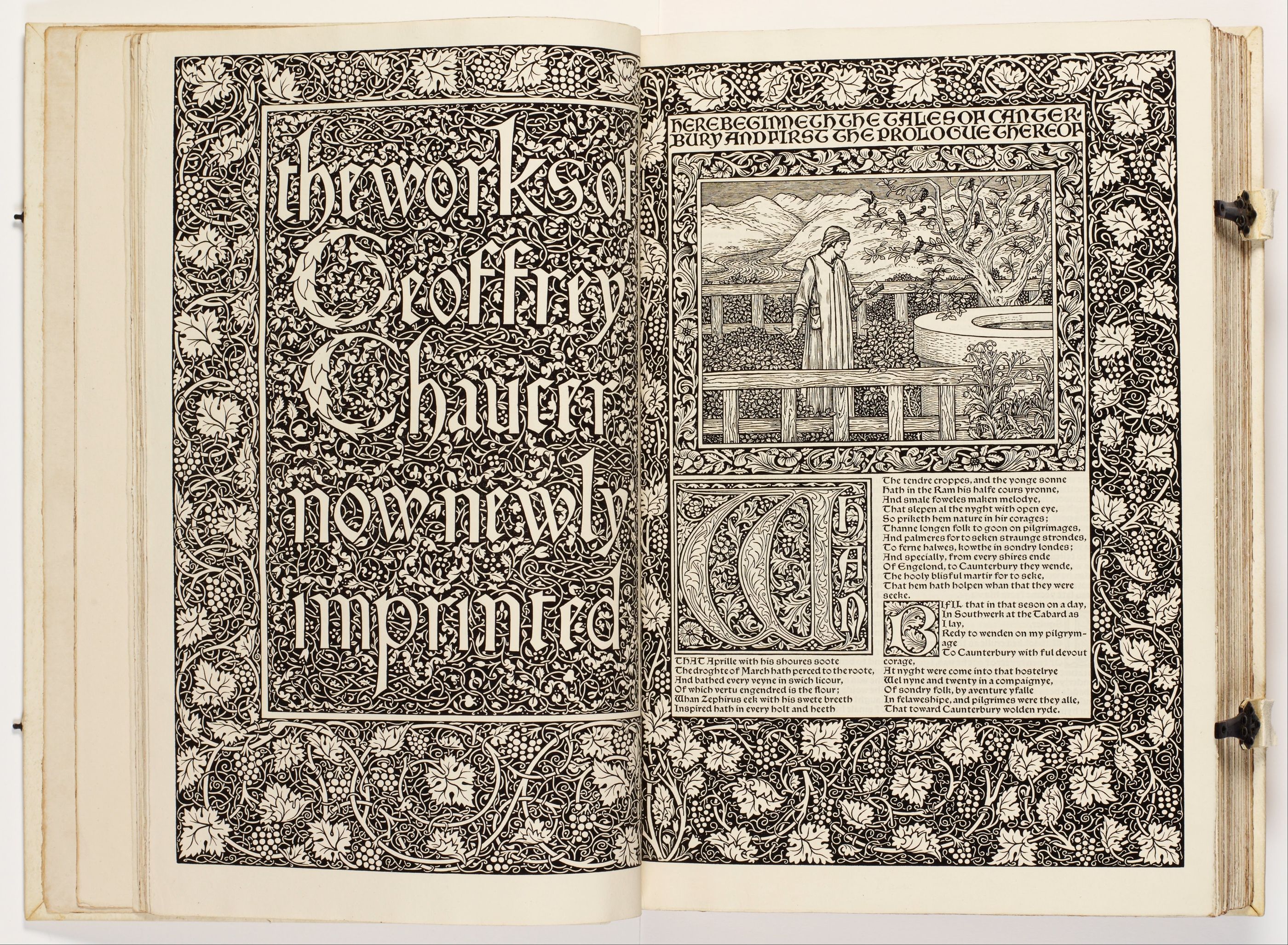 An open Kelmscott Chaucer, with an ornamental title page facing Chaucer in a garden above two columns of verse