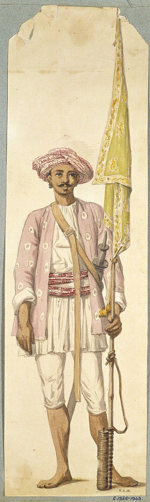 A painted figure in a patterned purple tunic and turban holding a long rocket as a flagstaff.