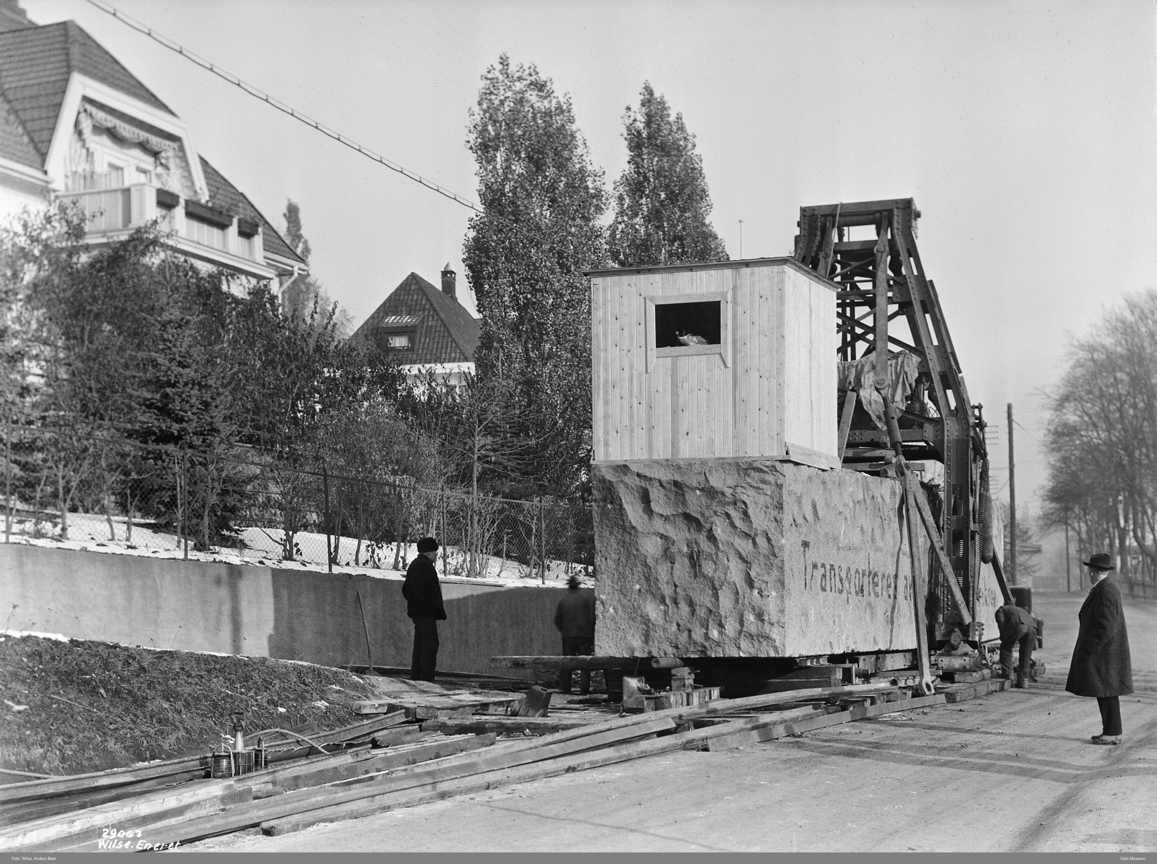 The squared Monolith block lying on temporary rails, with people beside it and a timber structure above.