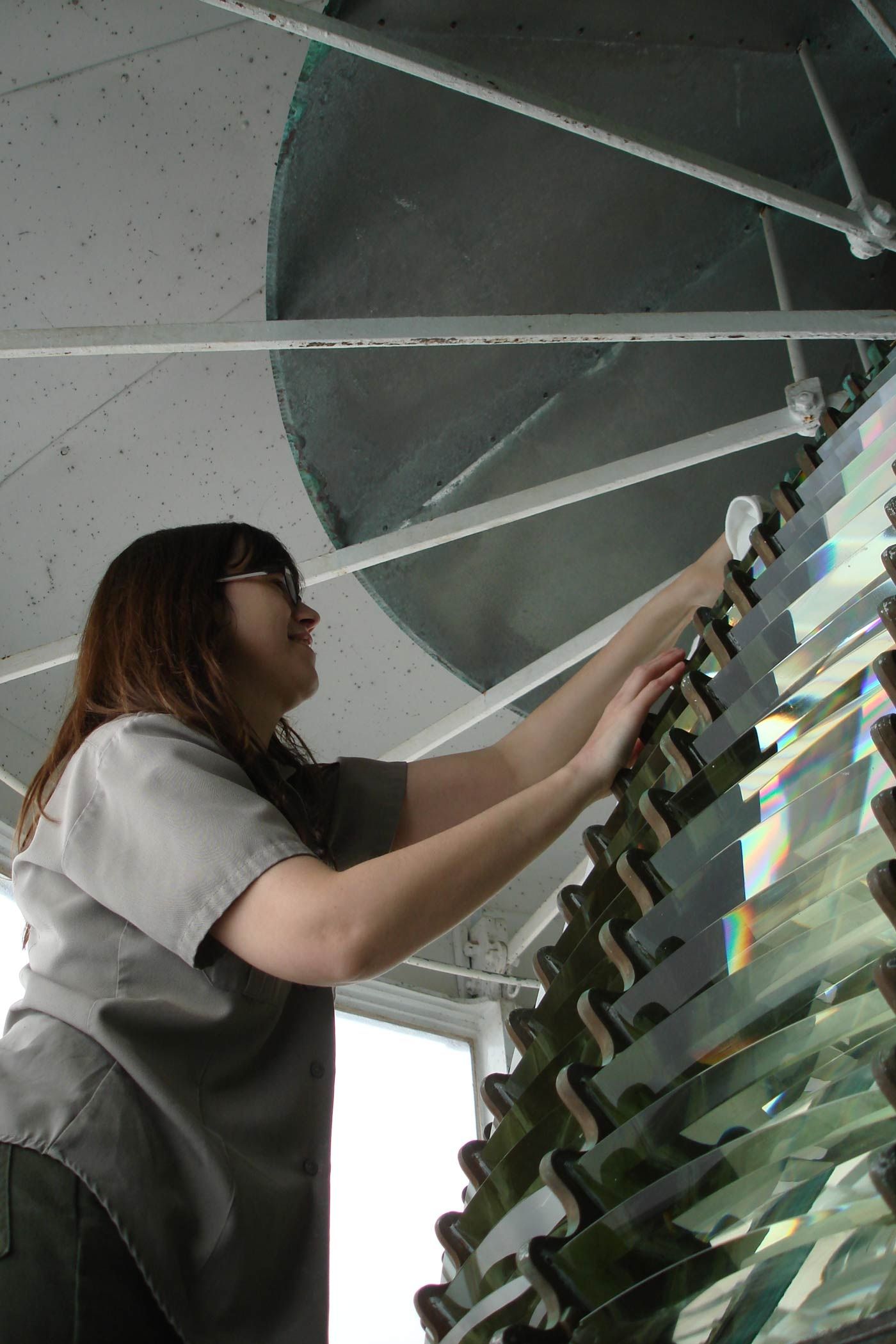 A park ranger cleaning an upper glass prism at Point Reyes with a white cloth