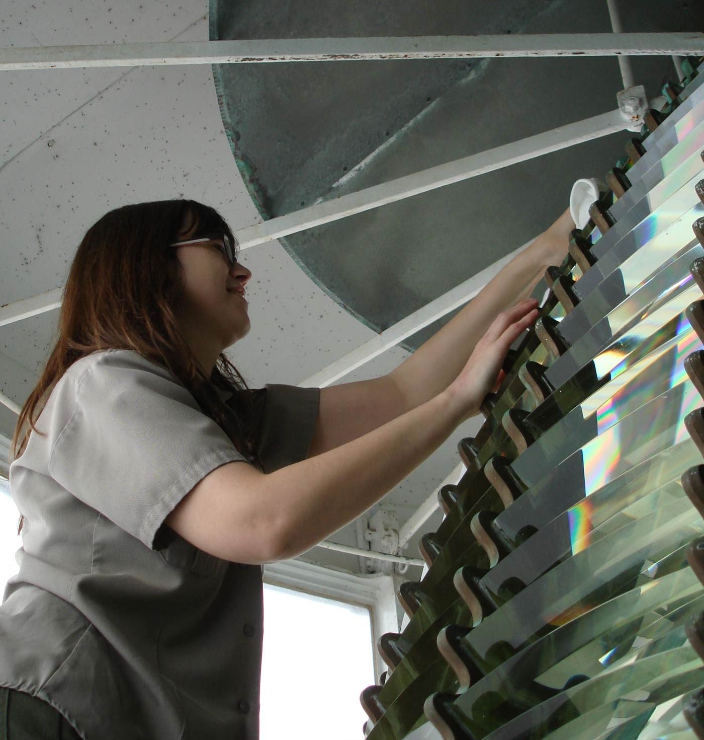 A park ranger cleaning an upper glass prism at Point Reyes with a white cloth