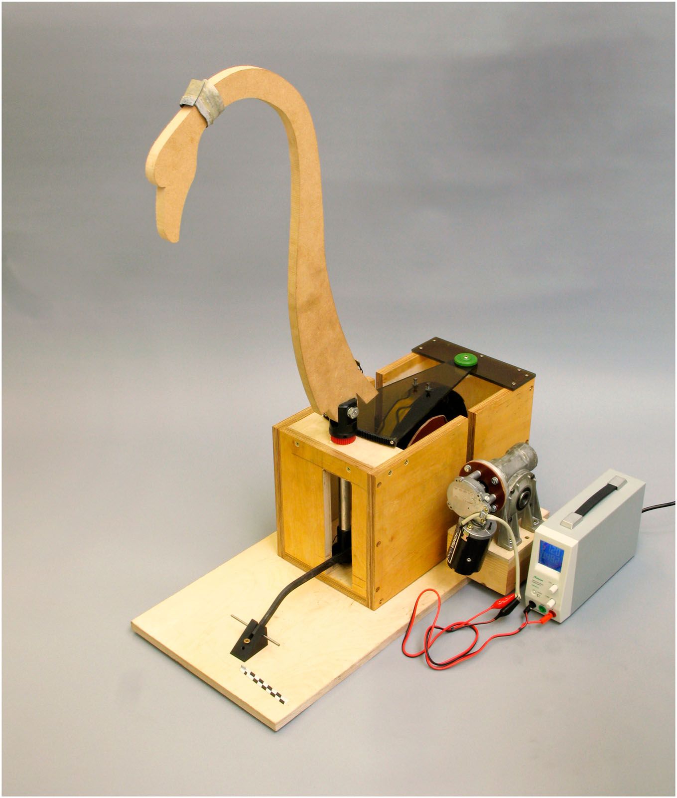 A plywood test machine with a simplified wooden swan neck and visible gears.