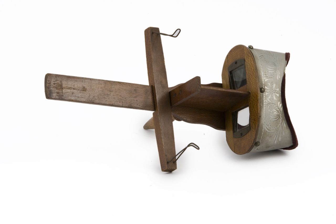 A wooden handheld stereoscope seen from the card side, with two lenses, a central divider and a sliding crosspiece with clips