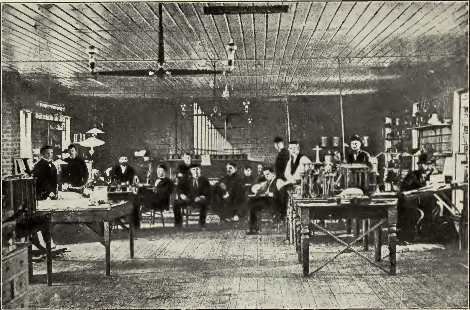 A long wooden laboratory room with benches, instruments and a group of people