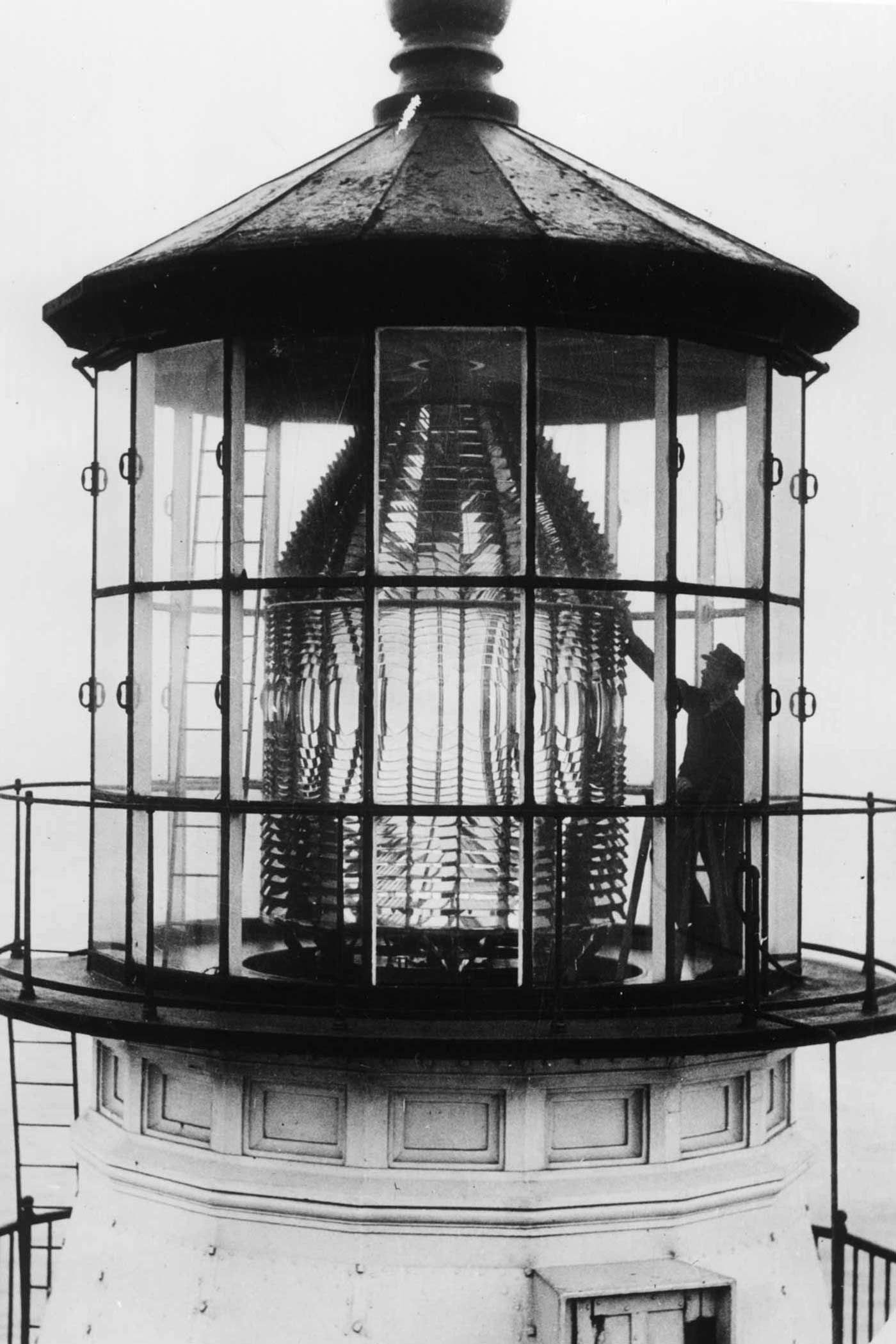 George Jaehne reaching up to clean the large glass lens inside the Point Reyes lantern