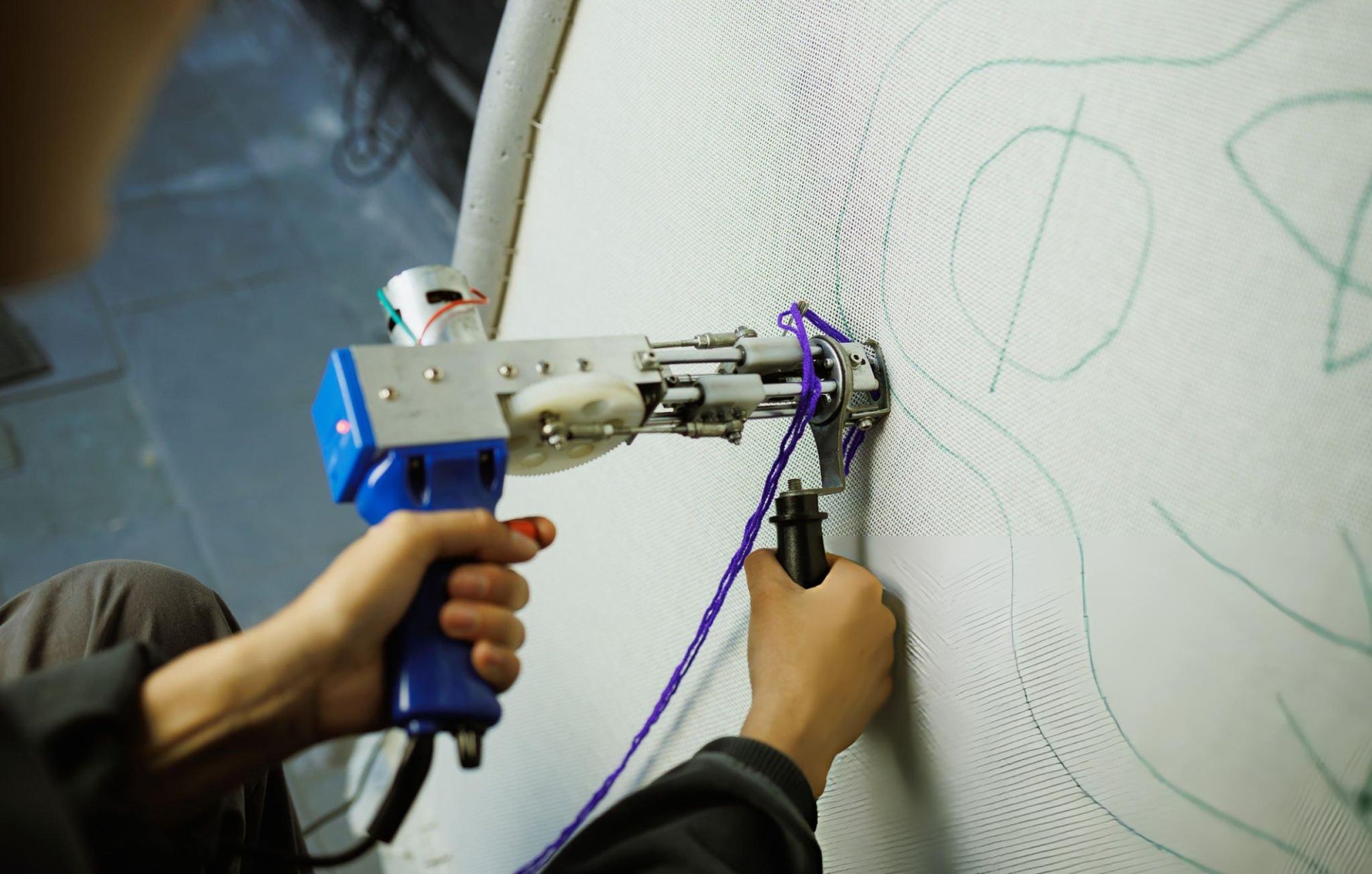 An artisan guiding a tufting gun across canvas