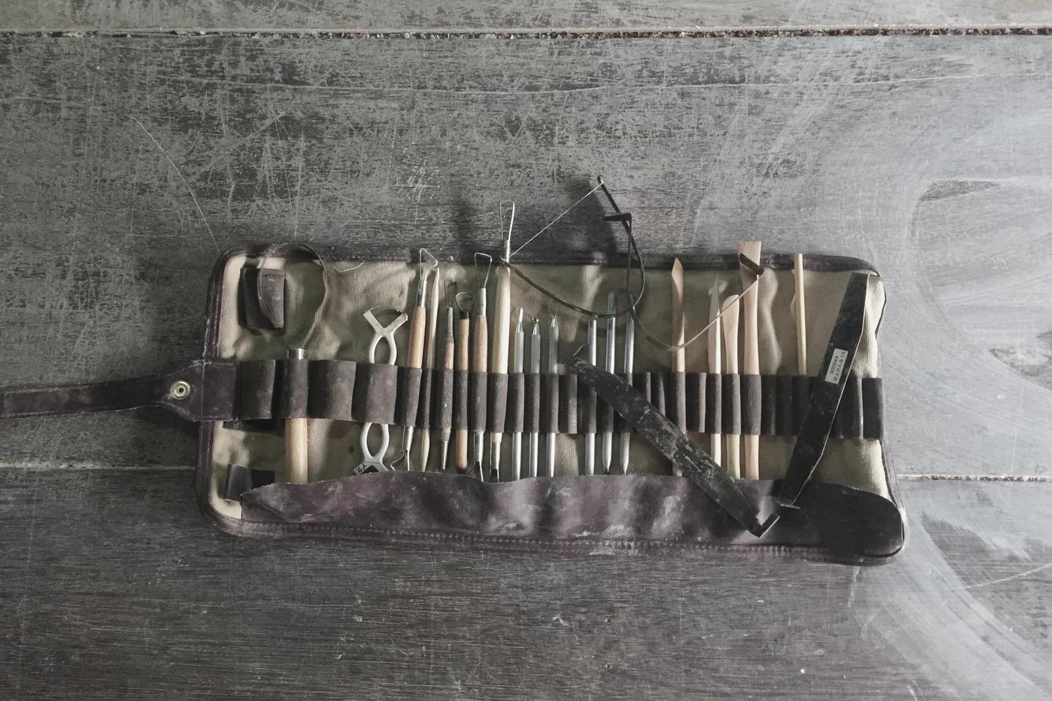 Pottery tools arranged on a worn studio worktable