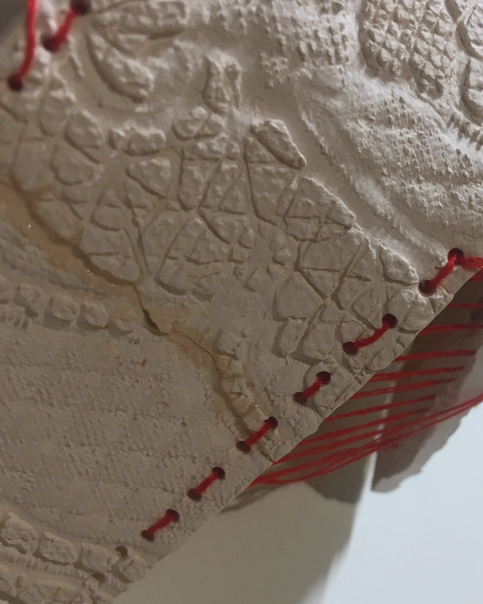 Red thread detail on clay letter F