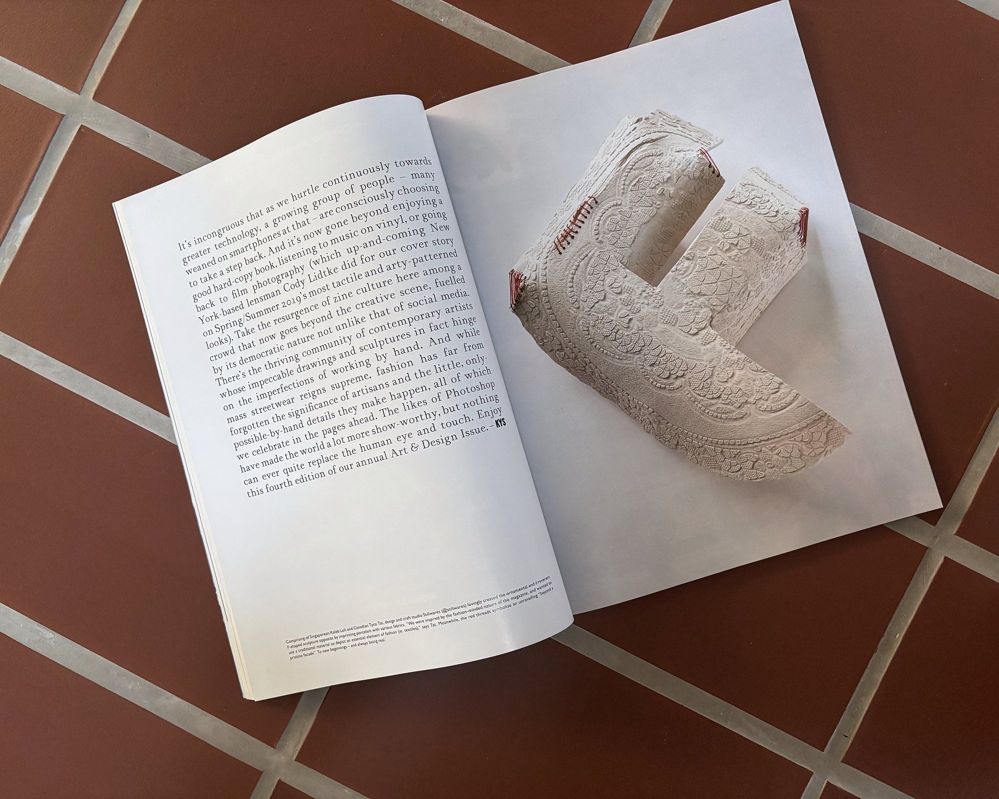 The porcelain F on white paper beside the open Female magazine, its printed article page visible.