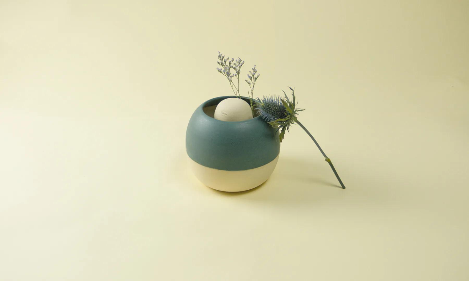 A green Restless vessel balanced on one of its two sides