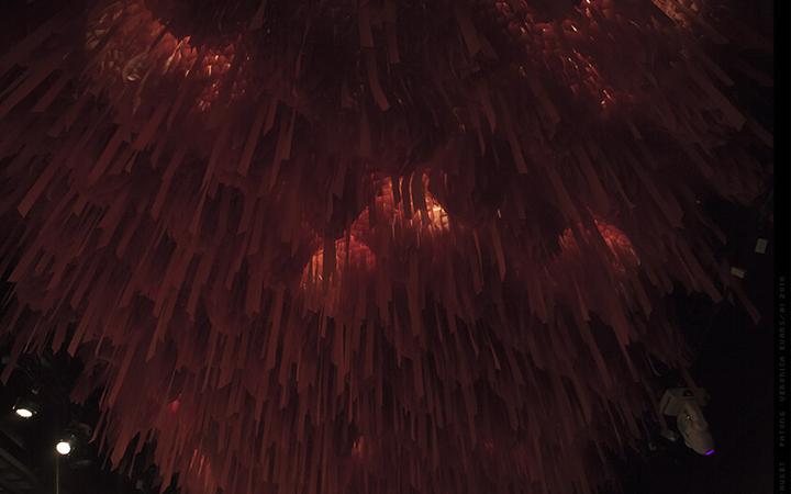 A ceiling densely covered with hanging reddish-brown ribbons, glowing with warm light.