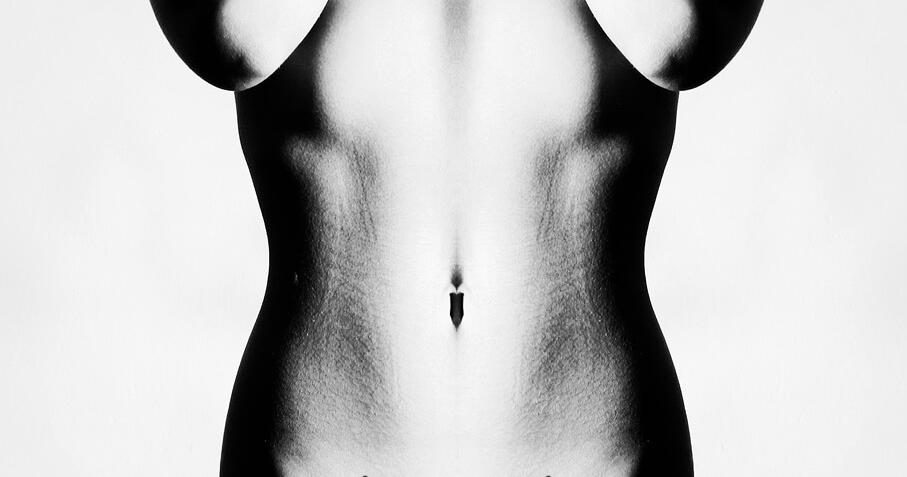 Symmetrical black and white photo of a bare human torso, featuring a navel and subtle body hair.