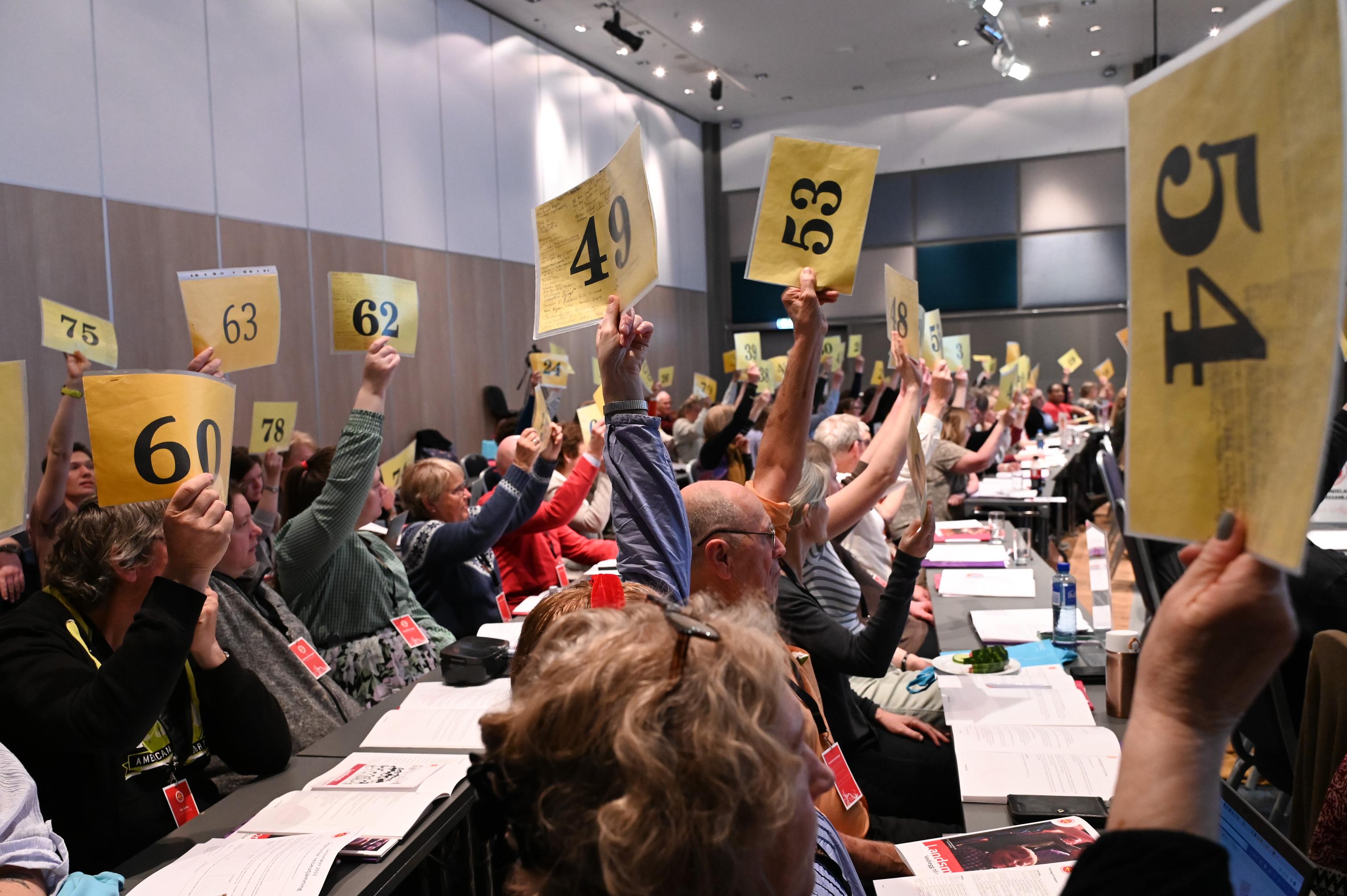 Landsmøtedelegatar stemmer ved å løfte gule lappar opp 