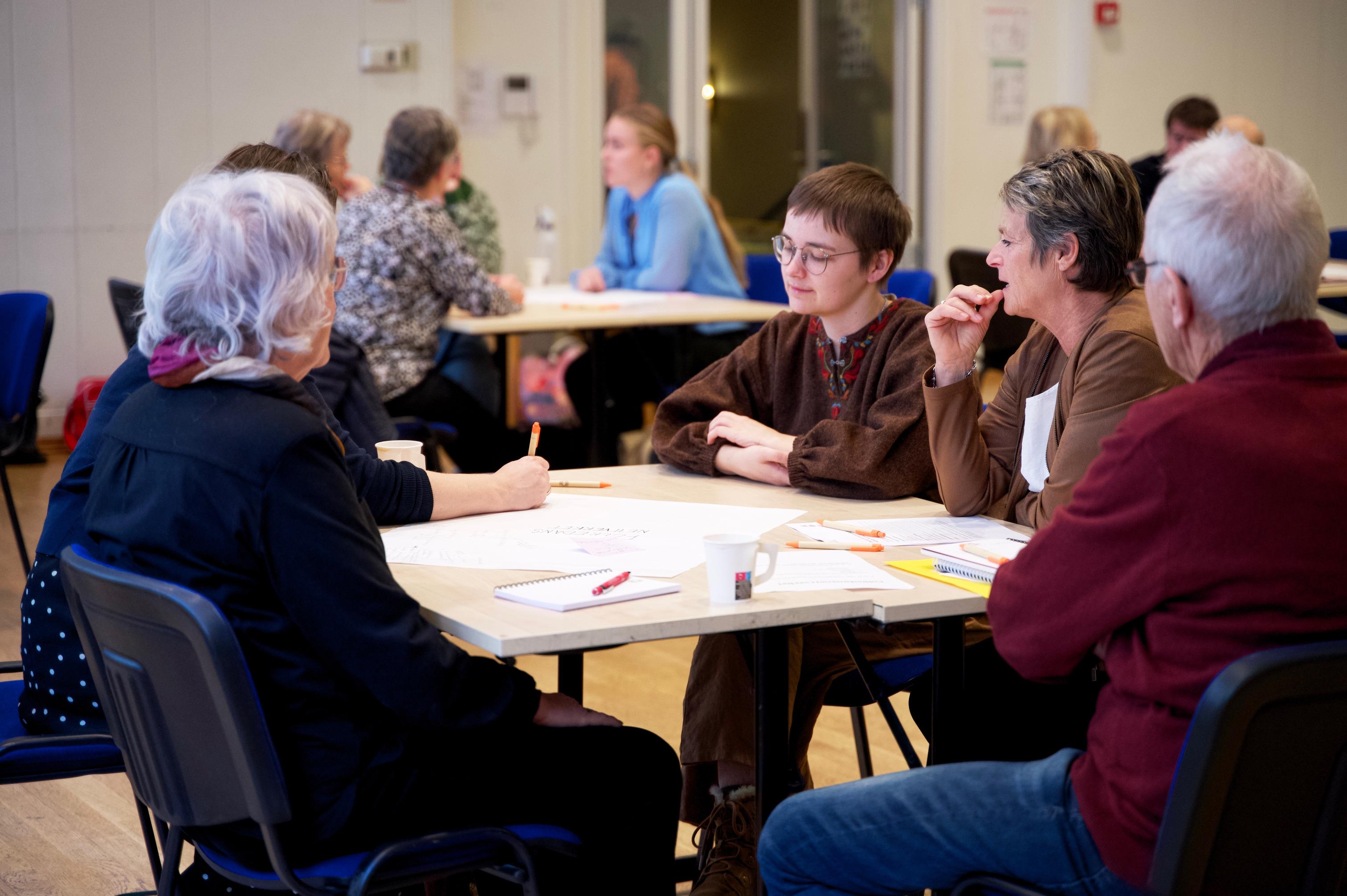 Ei gruppe personars om snakker saman rundt eit bord