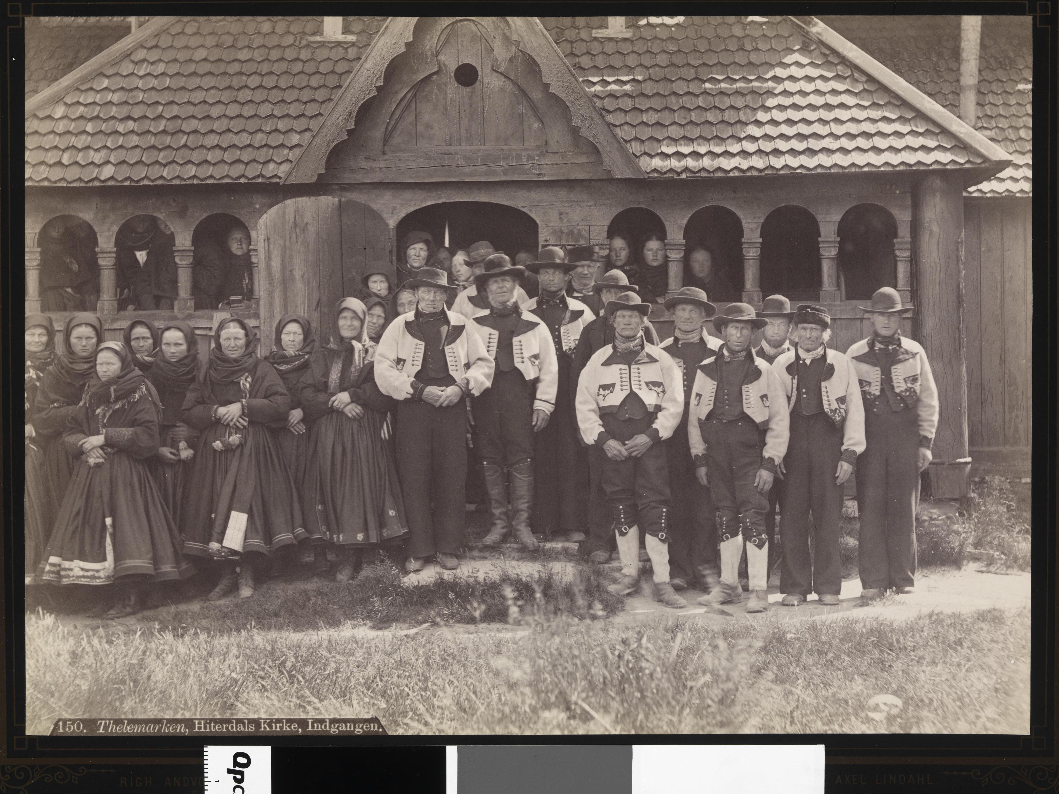 Ein gruppe kvinner og menn utanfor Heddal Stavkyrkje på 1800-talet, iført bunad
