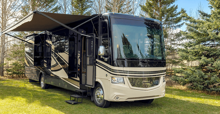 A Class A motorhome RV with its awning out, parked on a grassy field