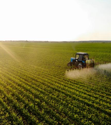 High-angle aerial view of a yellow combine harvester and a red tractor working together to harvest a grain field