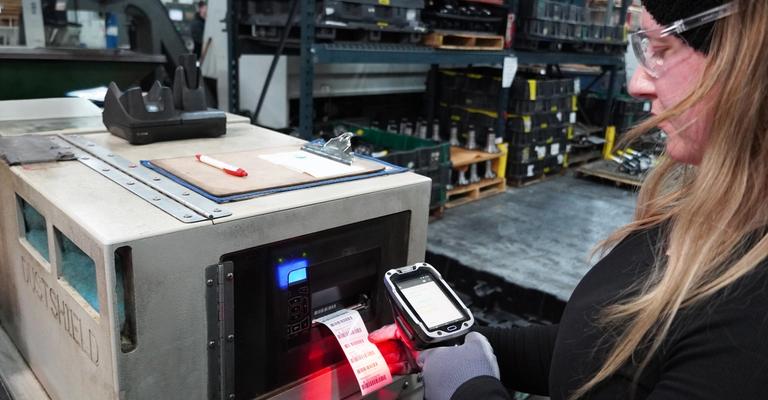 Worker uses a handheld digital scanner on a printed barcode label