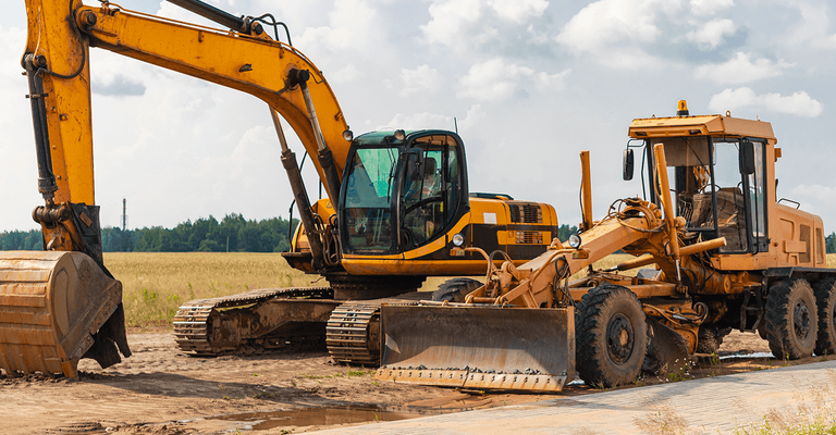 Industrial excavator and heavy machinery parked on a dirt worksite