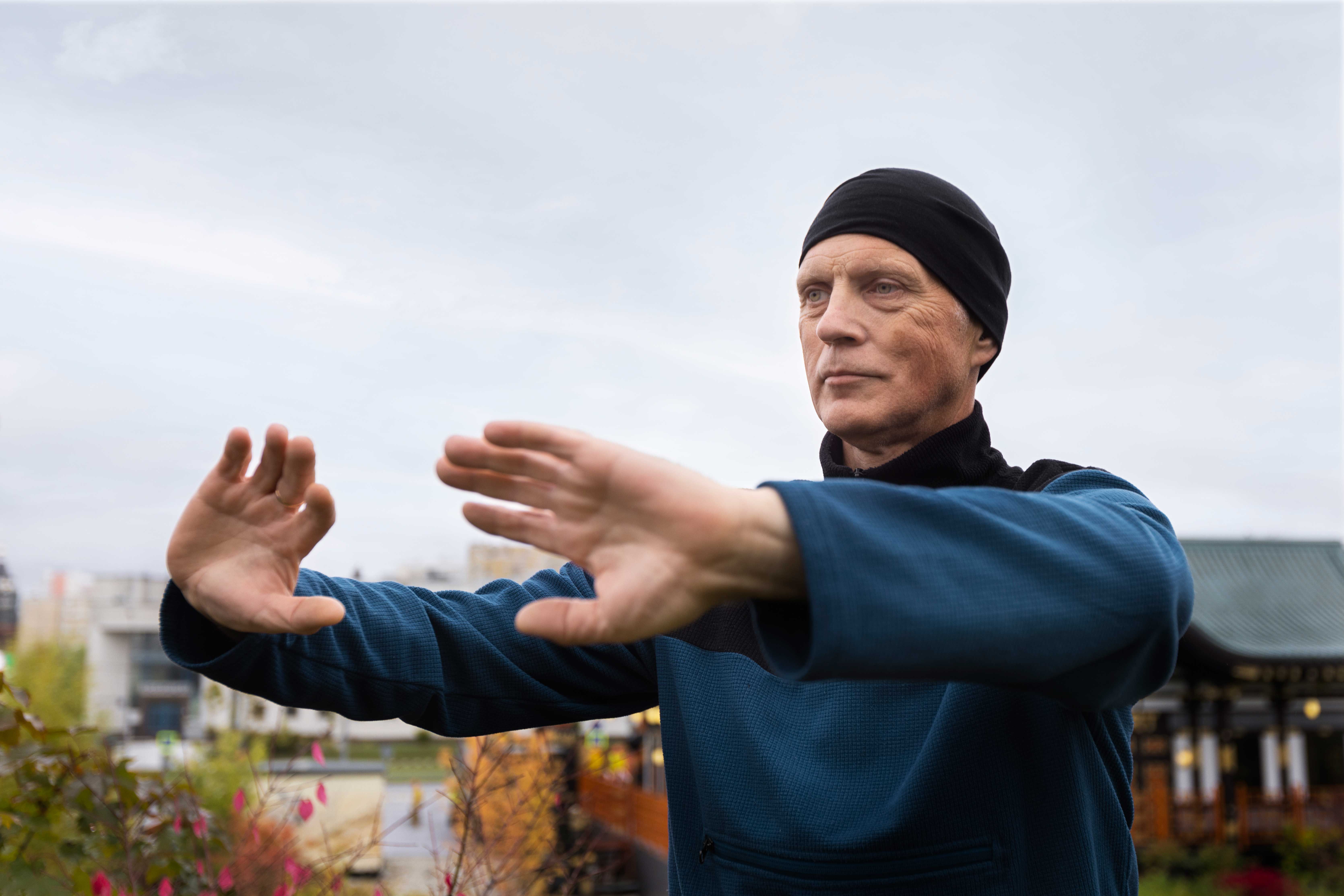 Un homme pratiquant le Qi Gong en plein air, effectuant des mouvements lents et fluides pour harmoniser son énergie vitale et renforcer son bien-être.