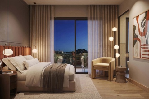 Bedroom at dusk with a terracotta leather headboard, globe lamps and a balcony.