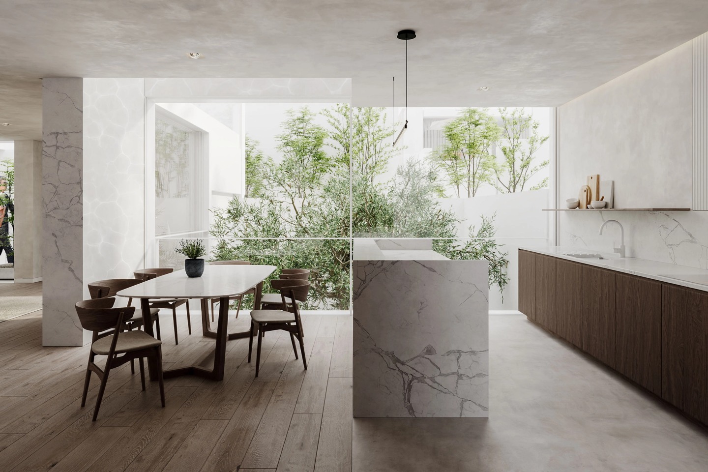Kitchen with a marble island and dining table, opening onto a courtyard with trees.