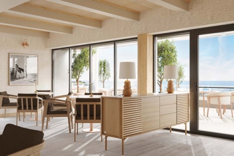 Dining room with a timber sideboard, table lamps and windows onto the sea.