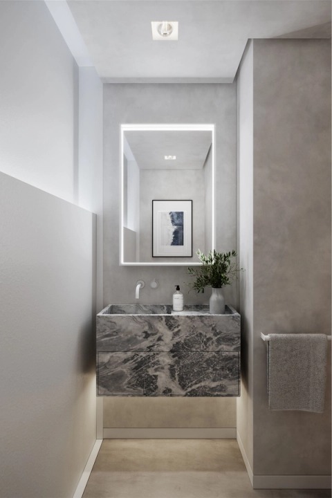 Guest bathroom with a dark marble vanity and an illuminated mirror.