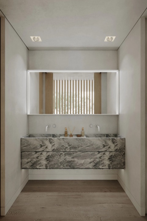 Bathroom with a double marble vanity and a wide illuminated mirror.