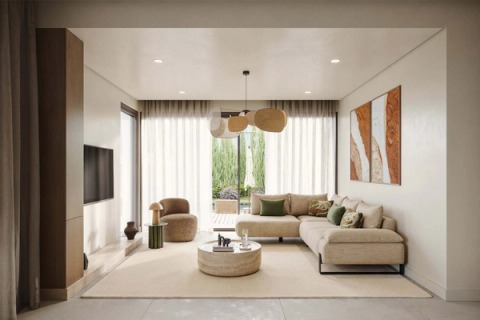 Living room with an L-shaped sofa, round coffee table and earth-toned artworks, opening onto the garden.
