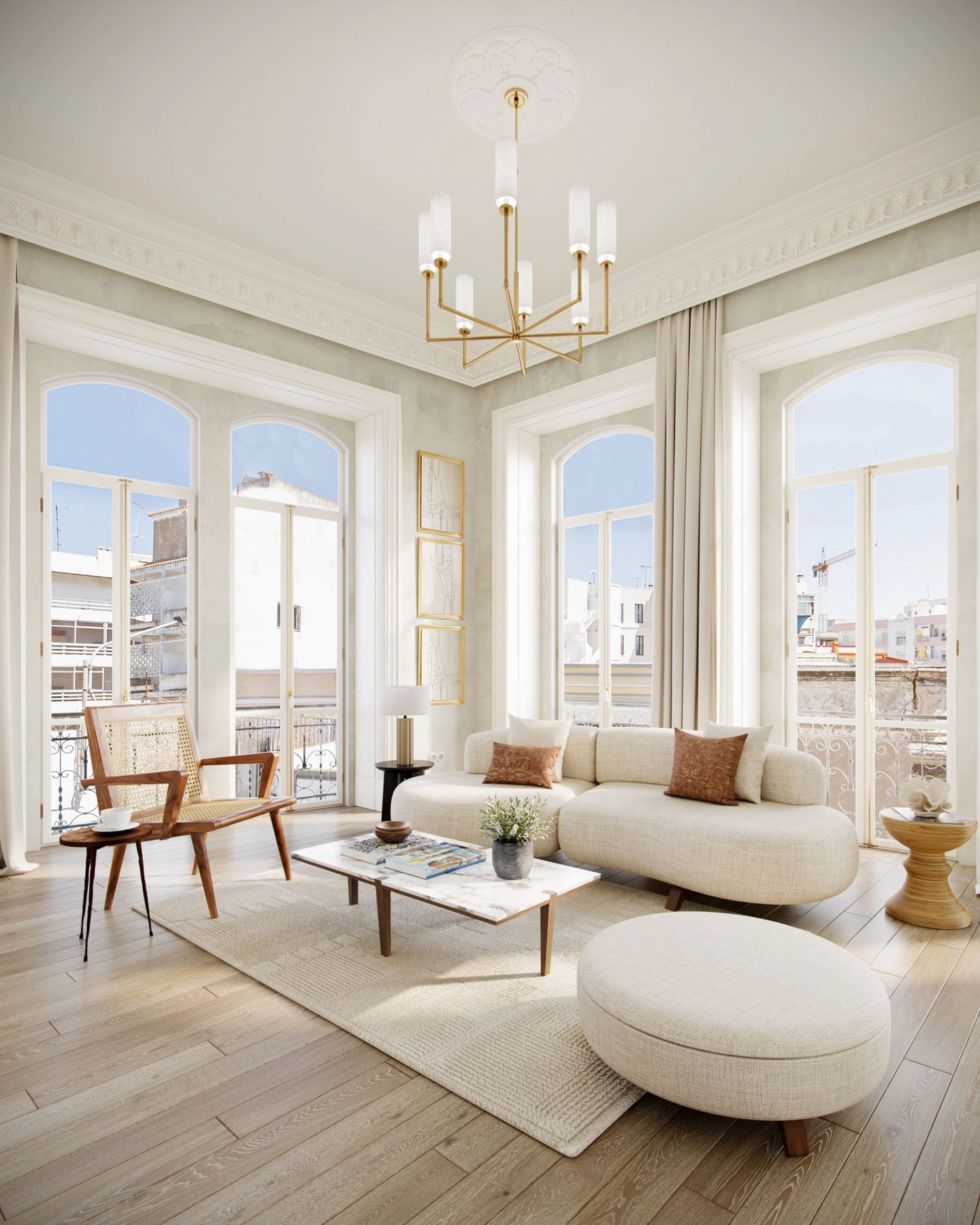 High-ceilinged living room with a brass chandelier, curved sofa and French windows, at Villa Pinto.