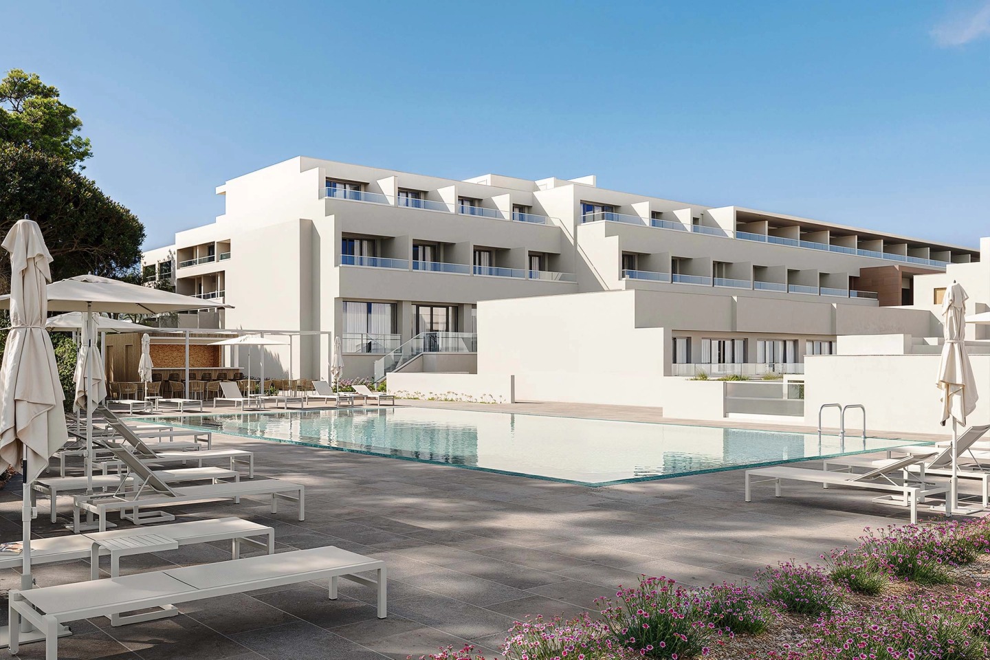 Outdoor pool at the Wyndham Grand Carvoeiro with white sun loungers and the terraced hotel building.