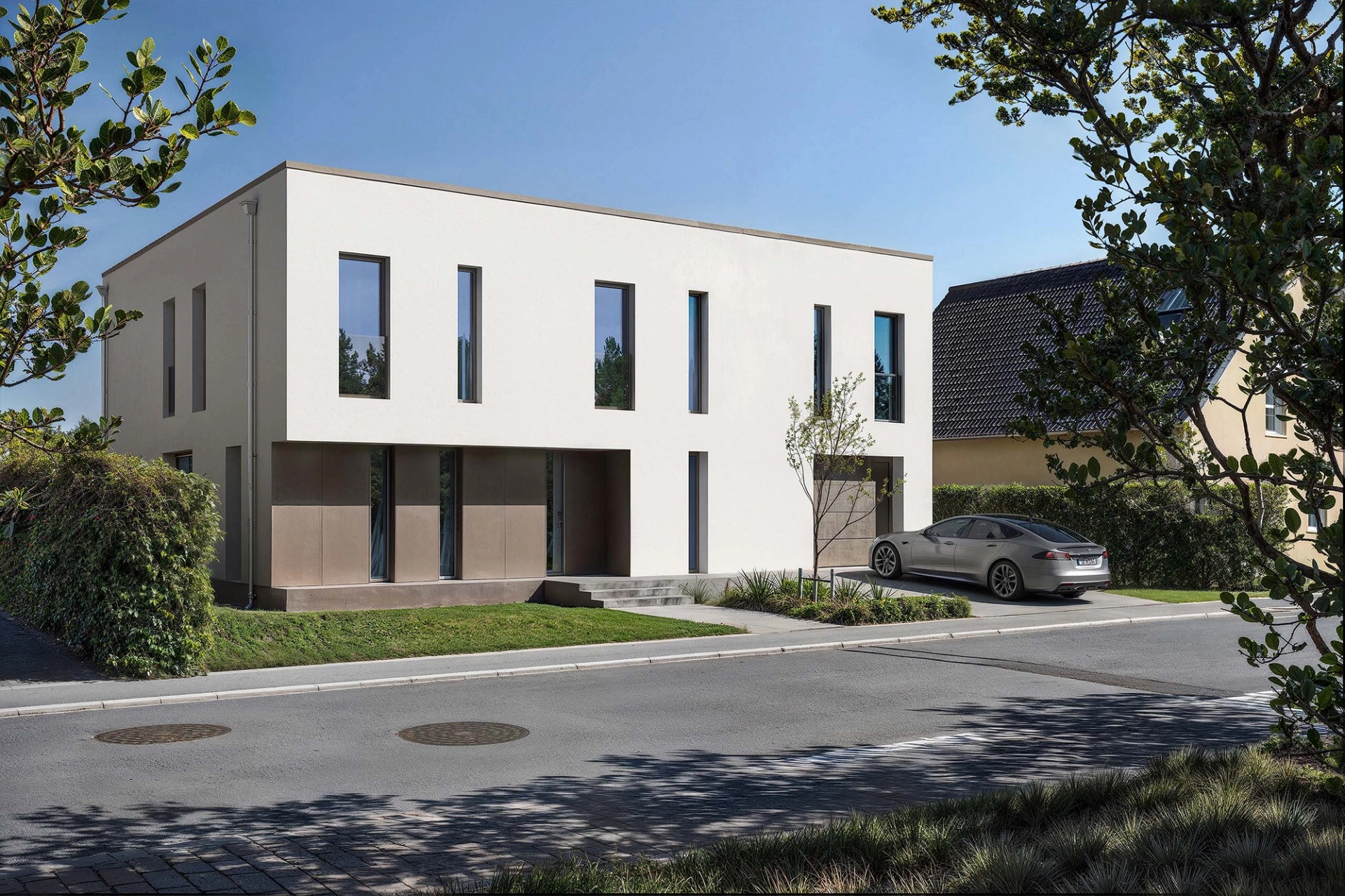 A house of simple lines in Junglinster, white with tall windows and a car parked outside.