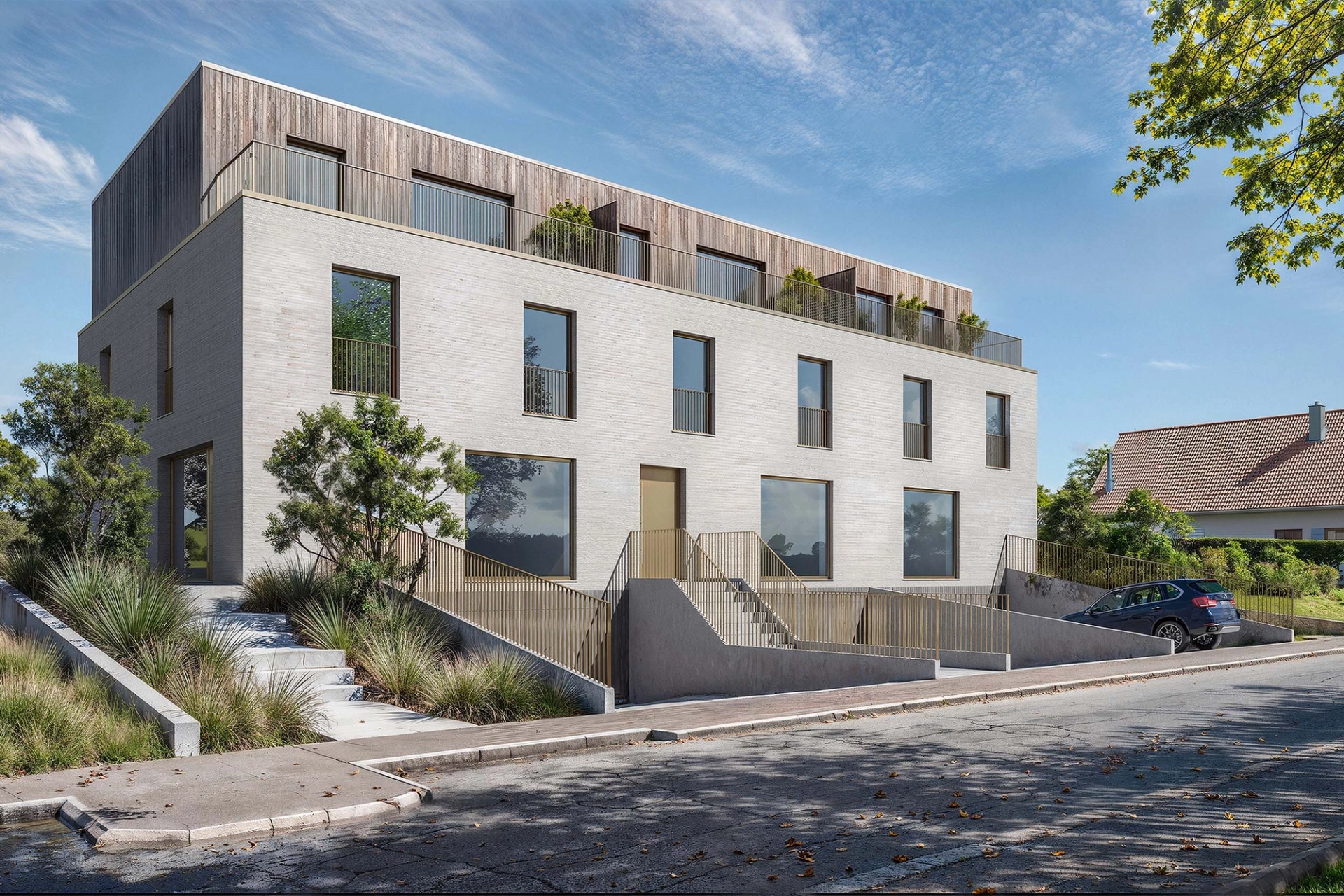 The Jowi building in Frisange, in light brick and timber, with a roof terrace and a garden down to the street.