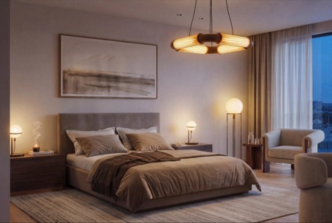 Earth-toned bedroom at dusk with lamps on and an armchair by the window.